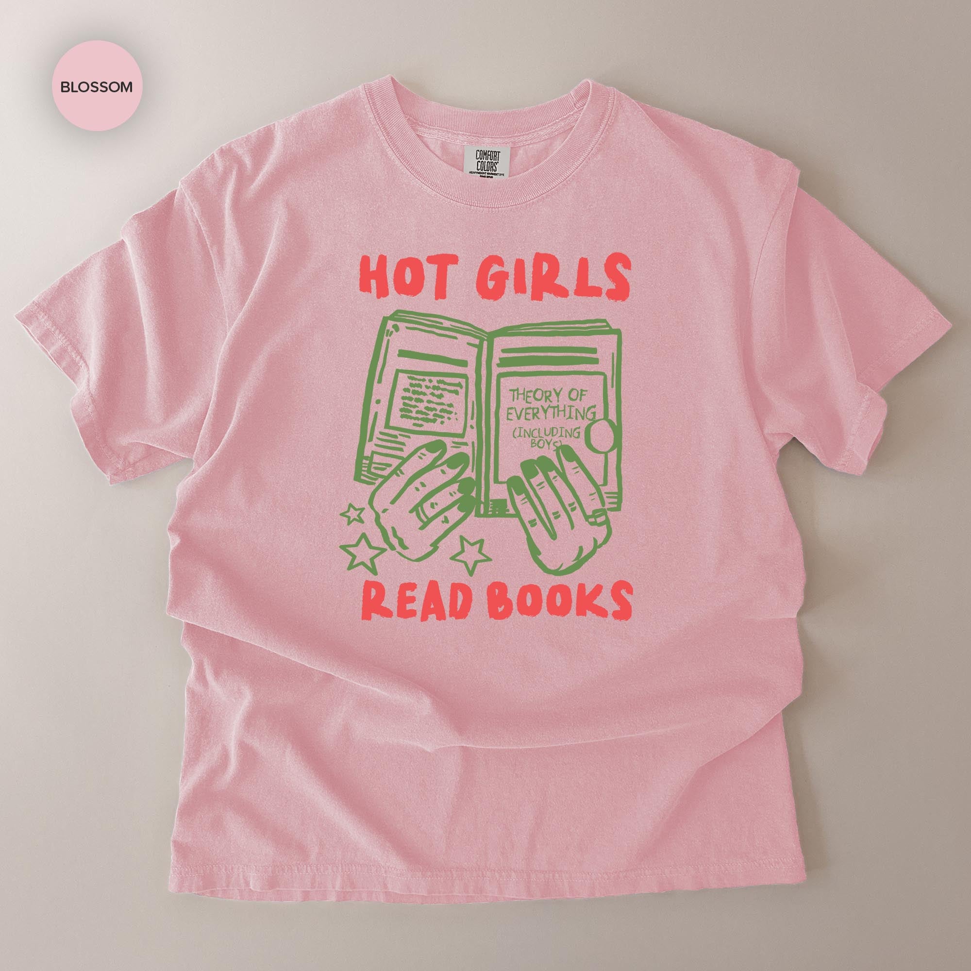 A pink t-shirt with a graphic design featuring a book and the text "HOT GIRLS READ BOOKS" printed on it.