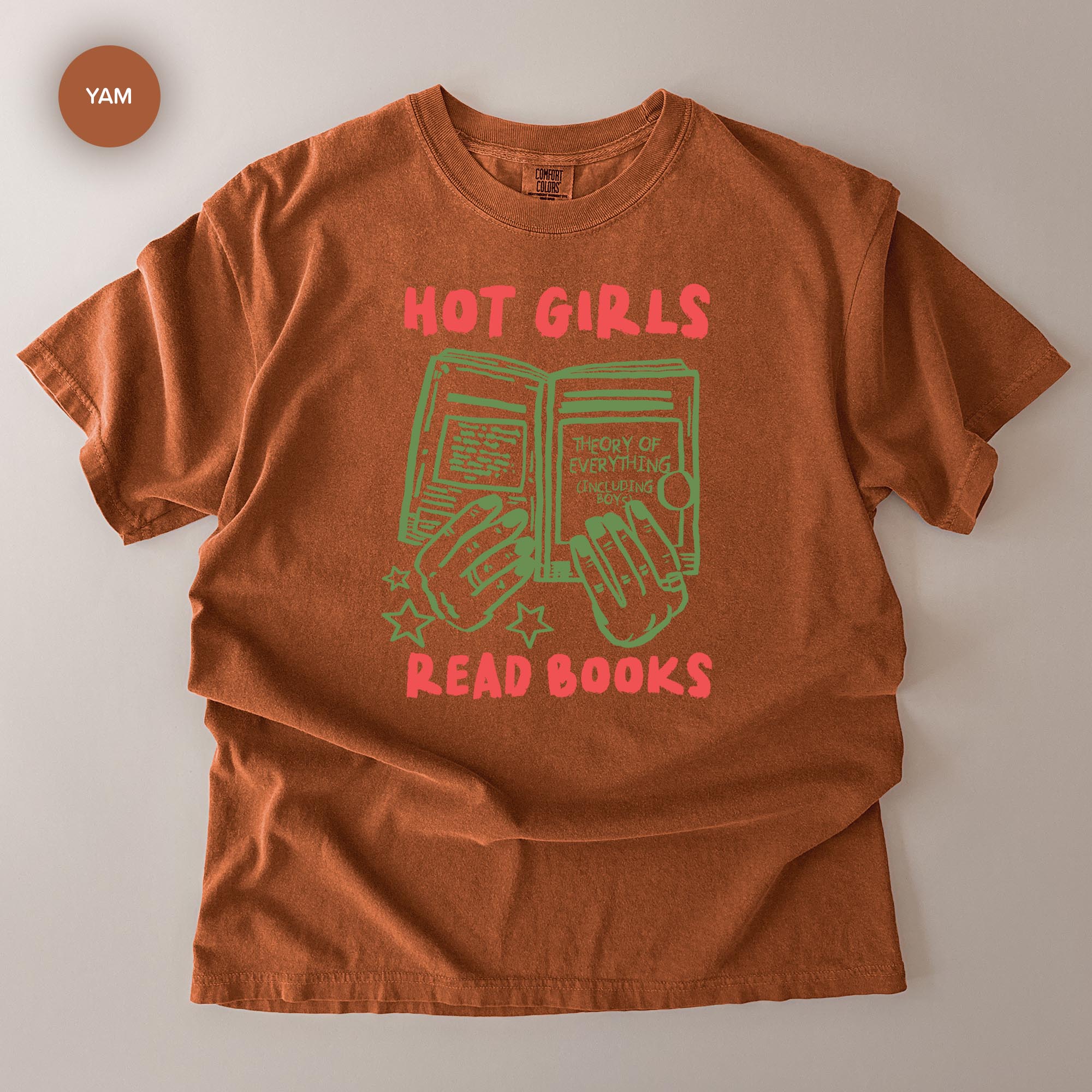 A brown t-shirt with a graphic design featuring a pair of hands holding an open book, along with the text "HOT GIRLS READ BOOKS" printed on it.