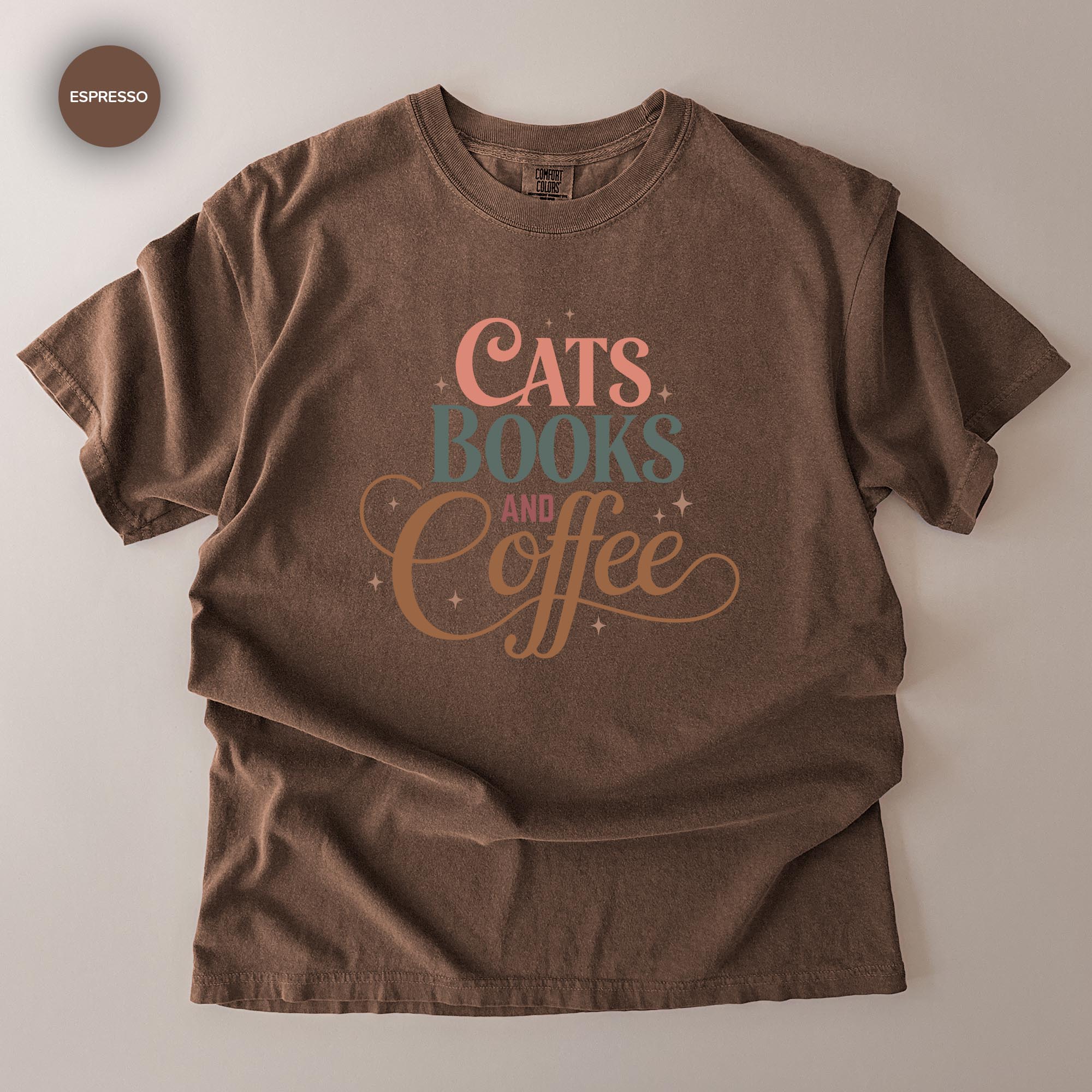 A brown t-shirt with a printed design that says "CATS BOOKS AND COFFEE" in a stylized font.