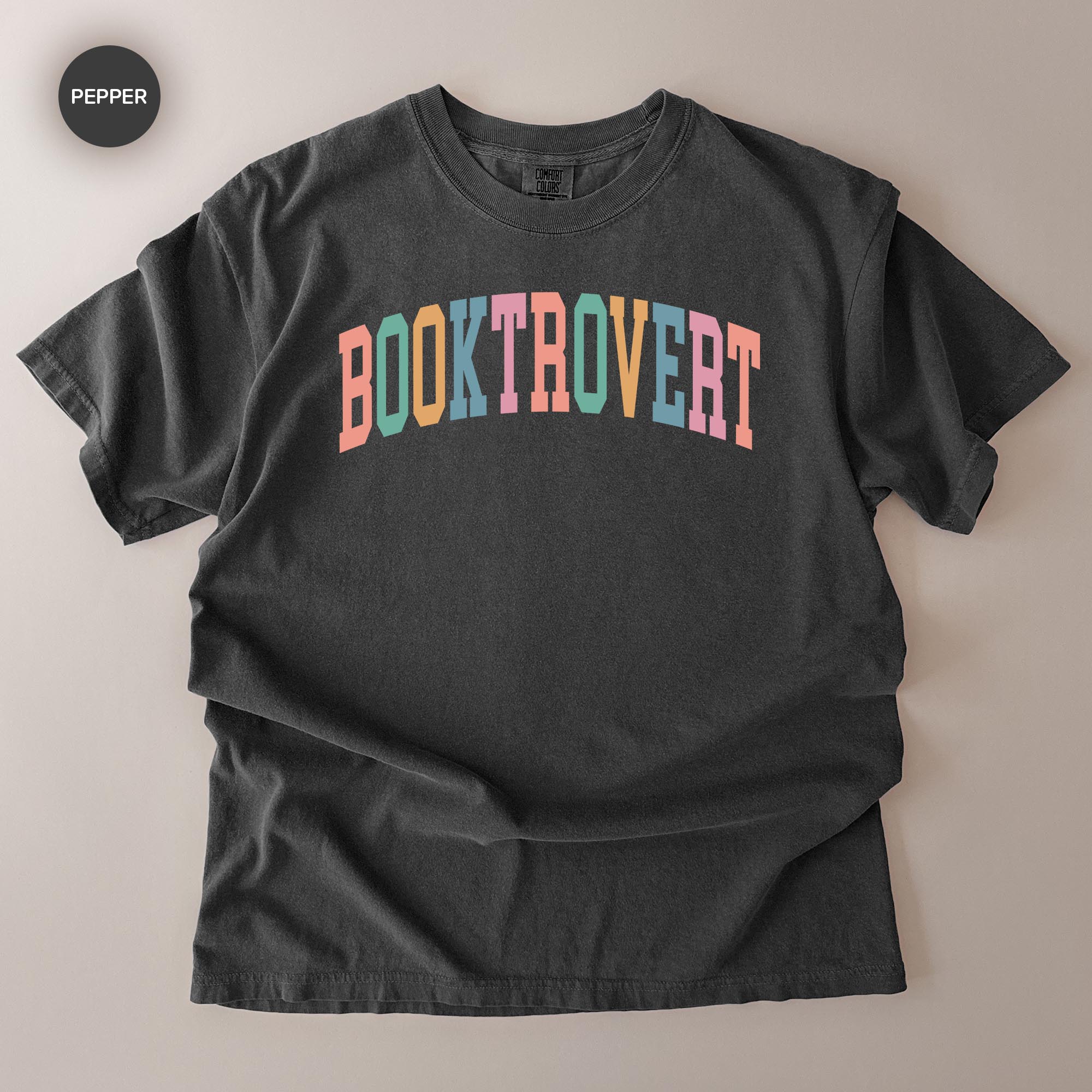 A black t-shirt with the text "BOOKTROVERT" printed in a colorful, multicolored font.
