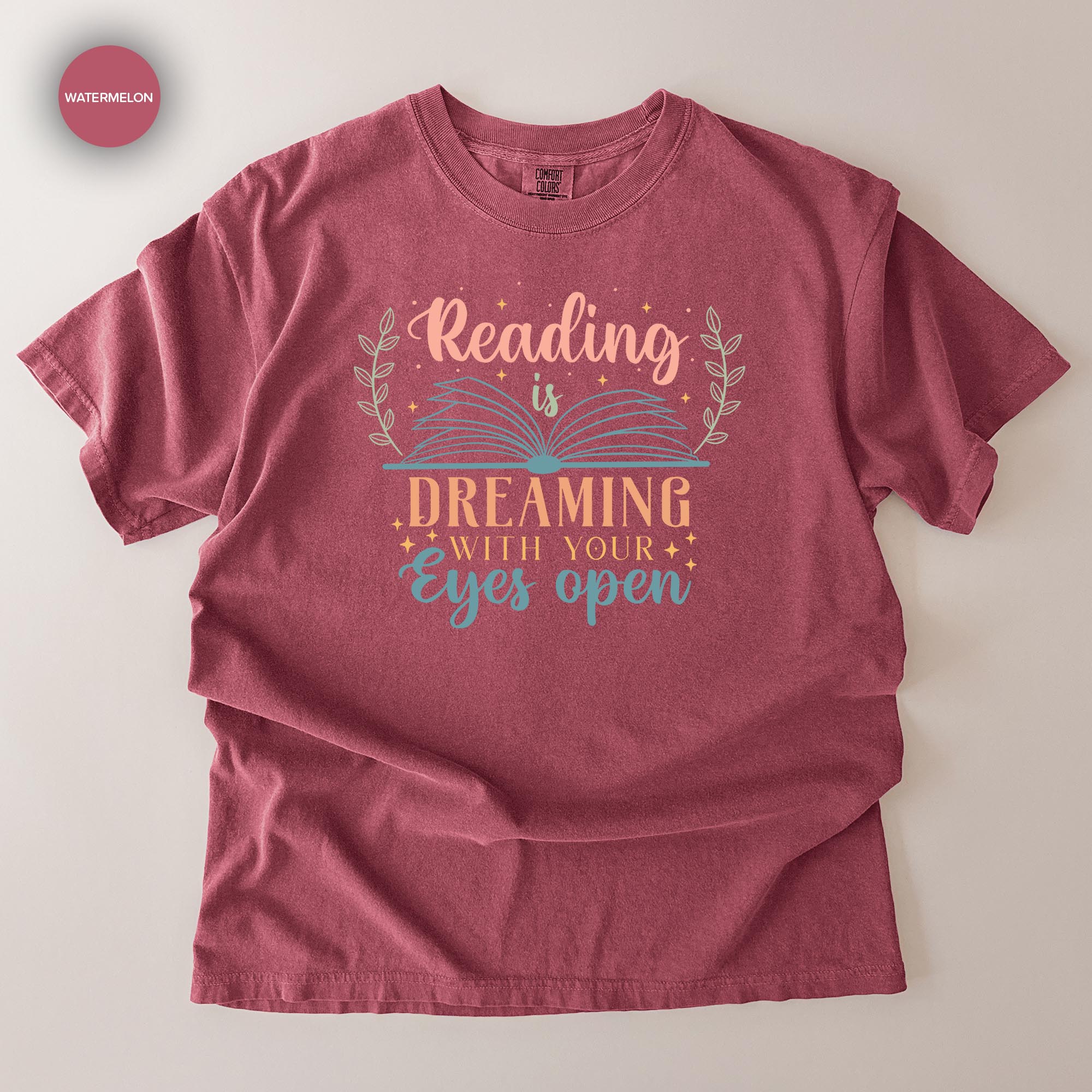 A red t-shirt with a printed design that says "Reading is Dreaming with your eyes open".