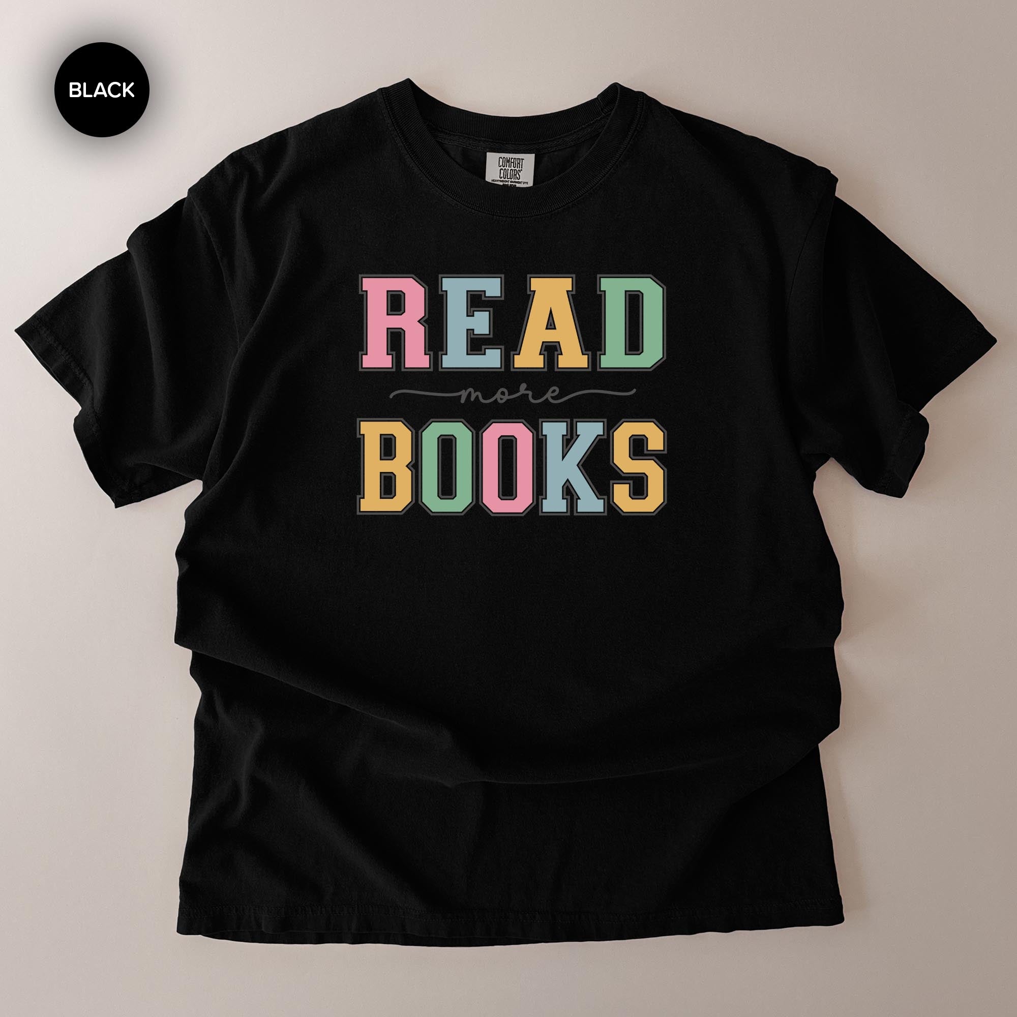 A black t-shirt with the text "READ MORE BOOKS" printed on it in a colorful, stylized font.