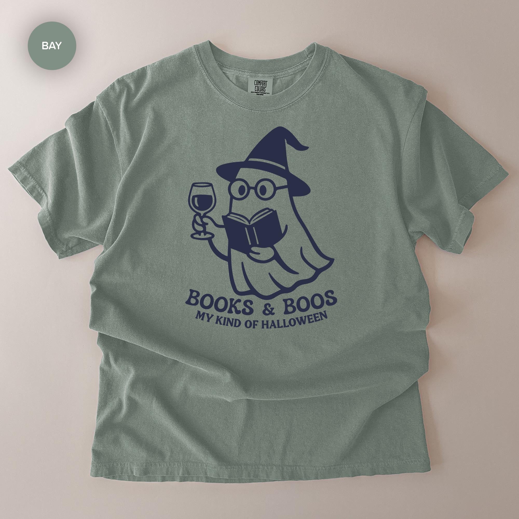 A t-shirt with a graphic design depicting a ghost character holding a book and a wine glass, with the text "Books & Boo's MY KIND OF HALLOWEEN" printed on it.