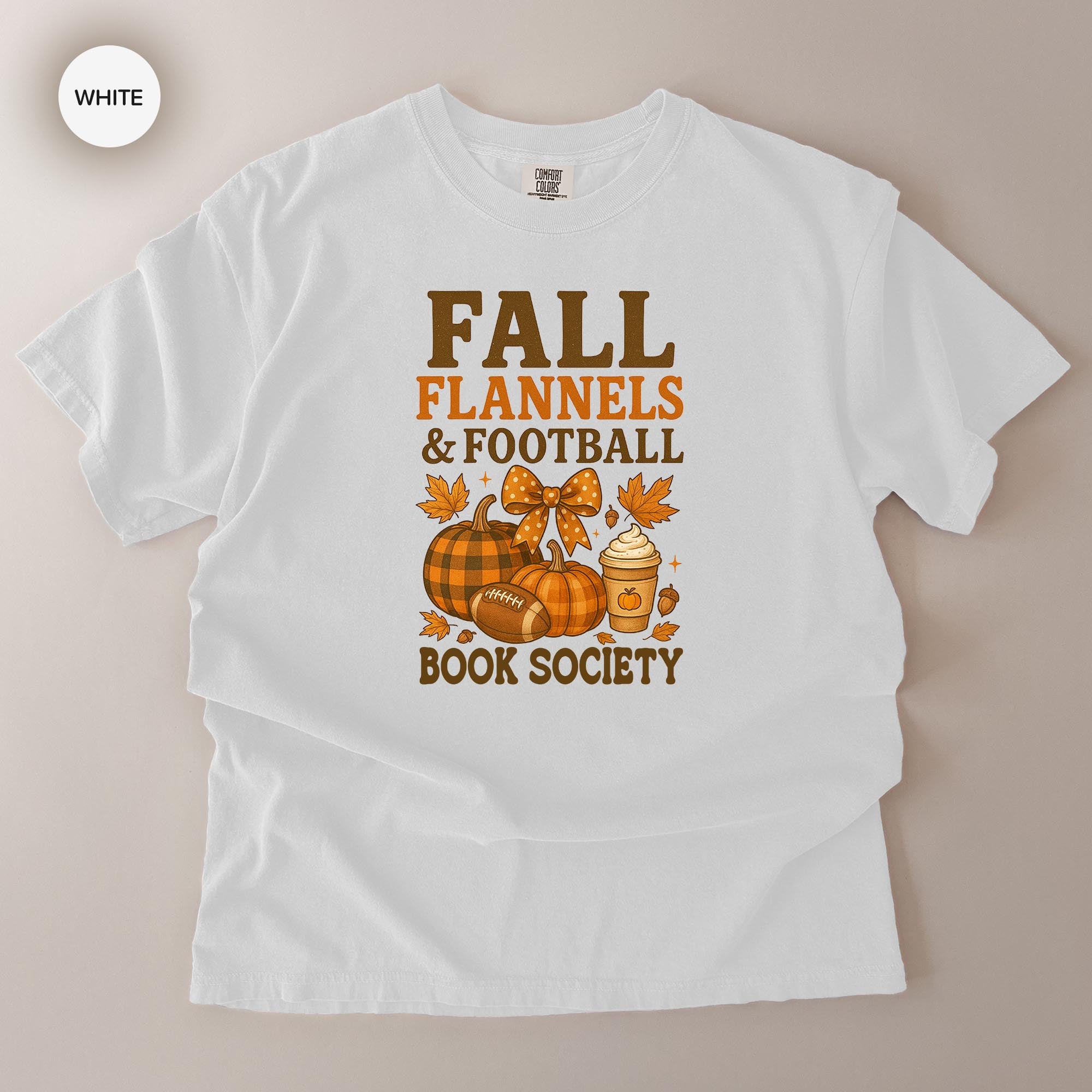 A white t-shirt with a graphic design featuring fall-themed elements such as pumpkins, footballs, and a book.