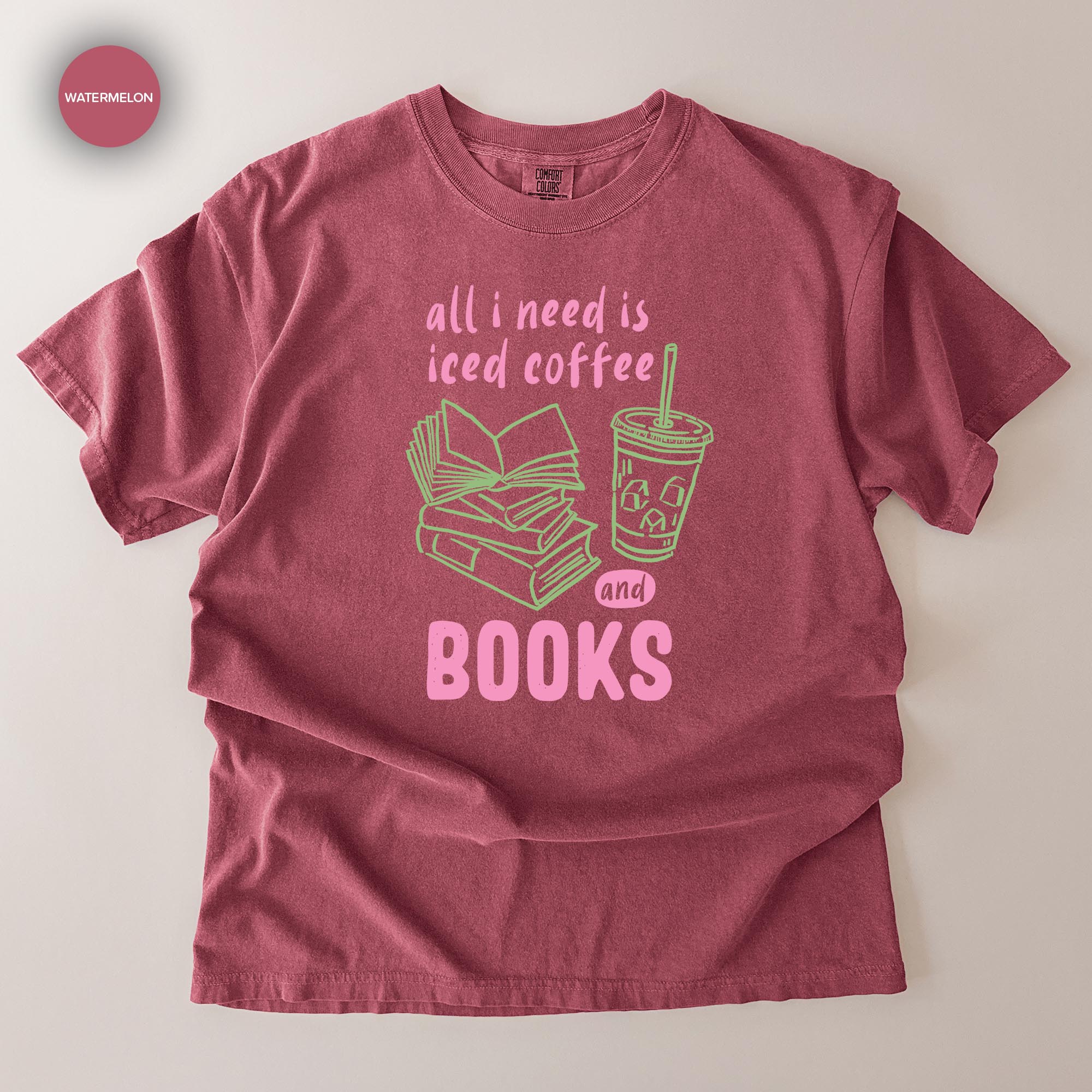 A red t-shirt with a graphic design that says "all I need is iced coffee and books" along with an illustration of a book and a cup of iced coffee.