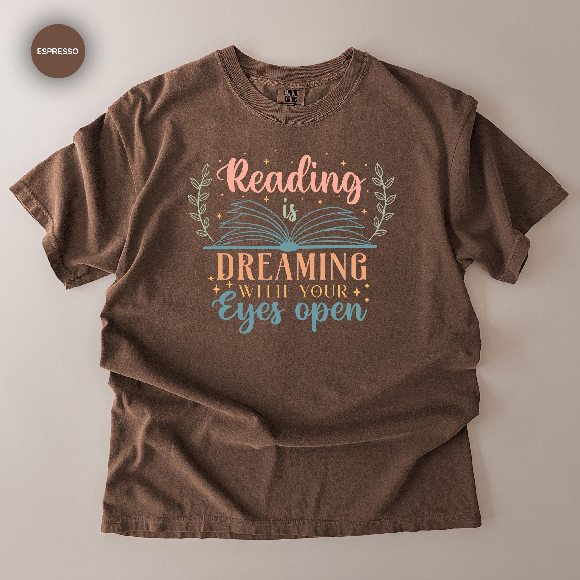 A brown t-shirt with a printed design that says "Reading is Dreaming with your eyes open".