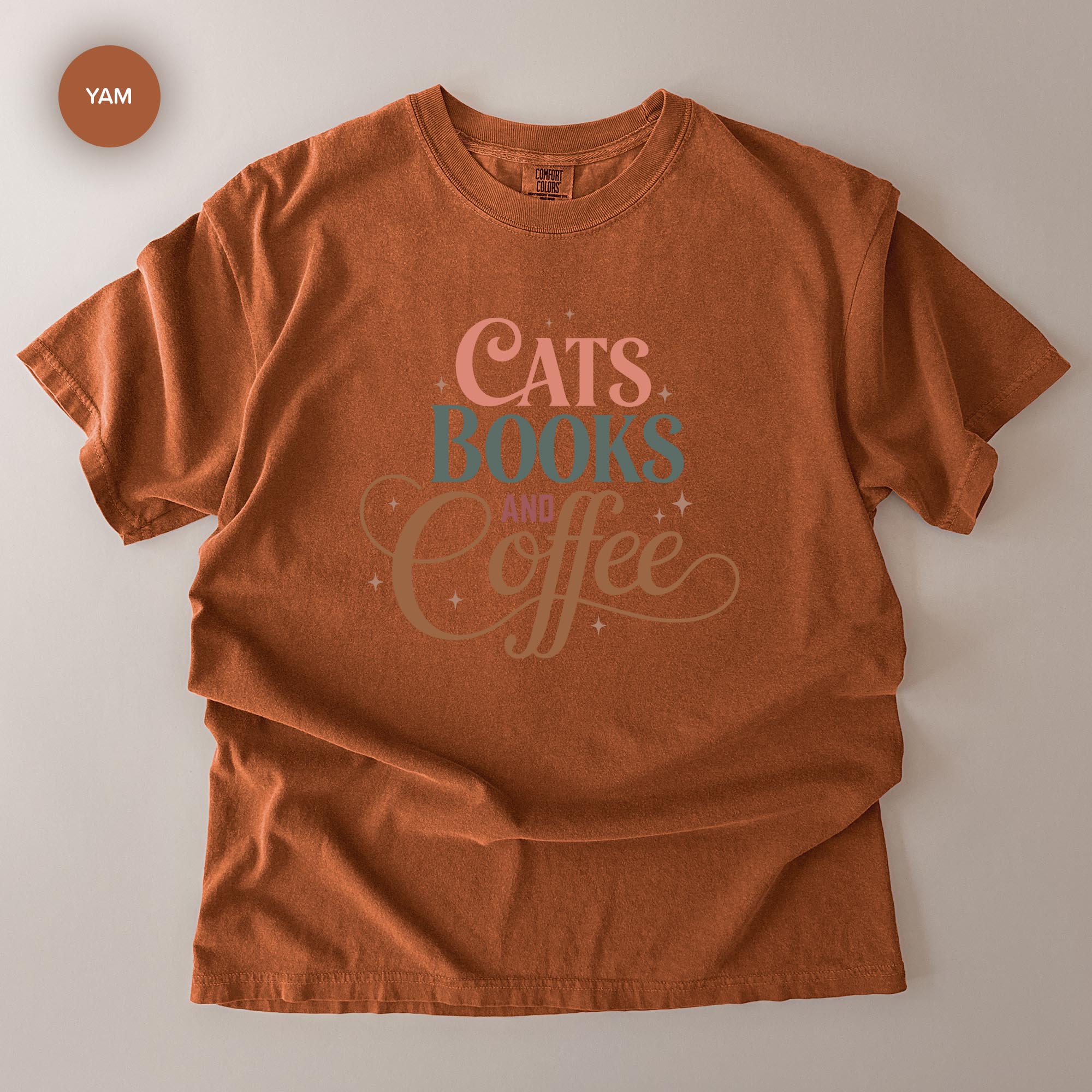 A red t-shirt with the text "CATS BOOKS AND COFFEE" printed on it.