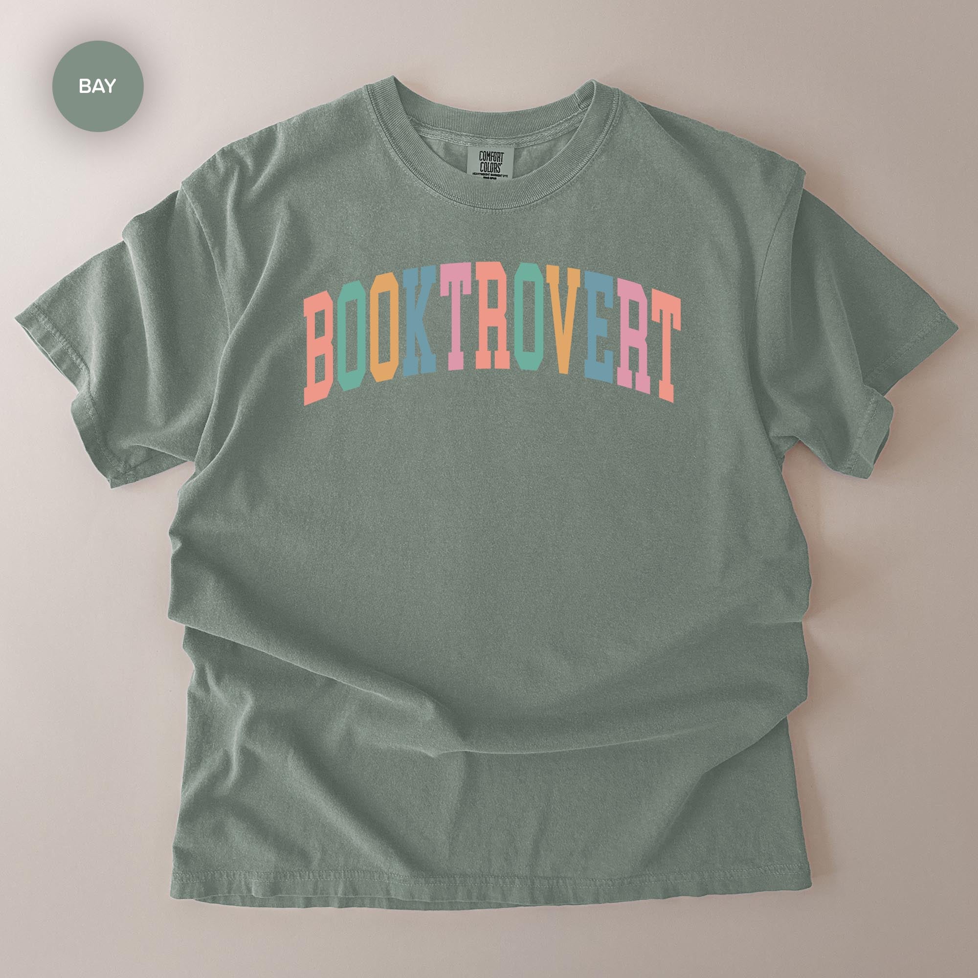 A gray t-shirt with the text "BOOKTROVERT" printed in a colorful, vibrant font.