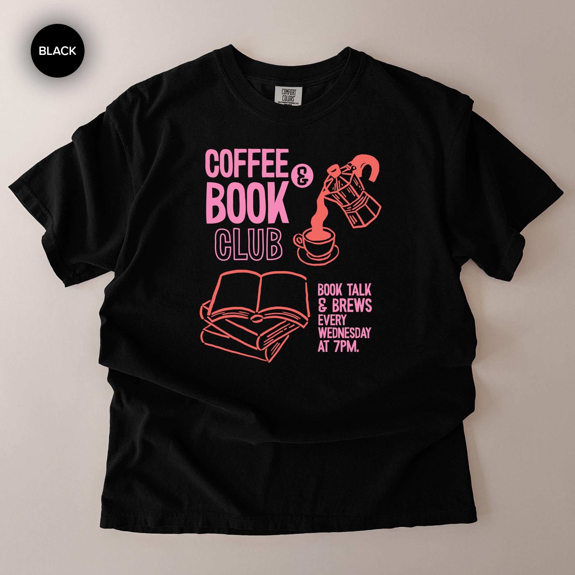 A black t-shirt with a graphic design featuring a coffee cup, a book, and text that reads "COFFEE BOOK CLUB BOOK TALK & BREWS 7PM WEDNESDAY".