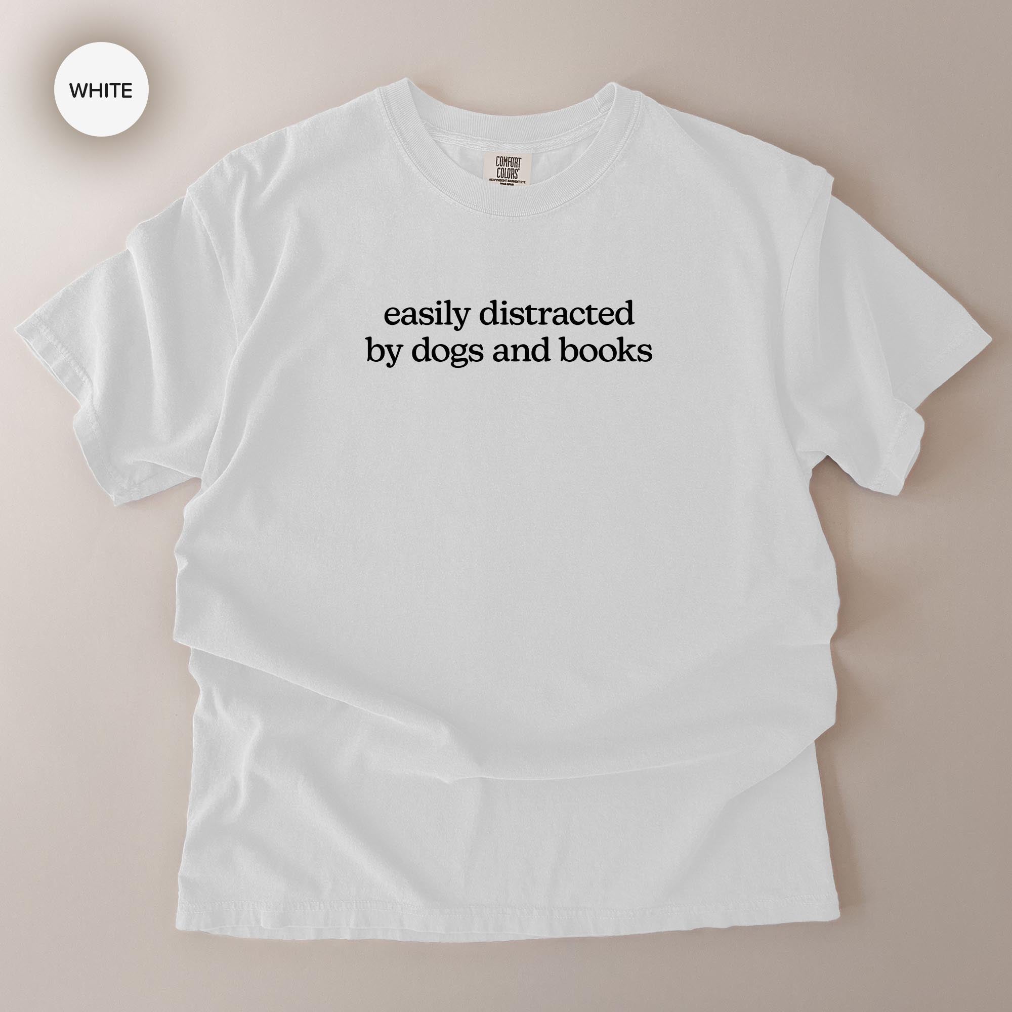 A white t-shirt with the text "easily distracted by dogs and books" printed on it.