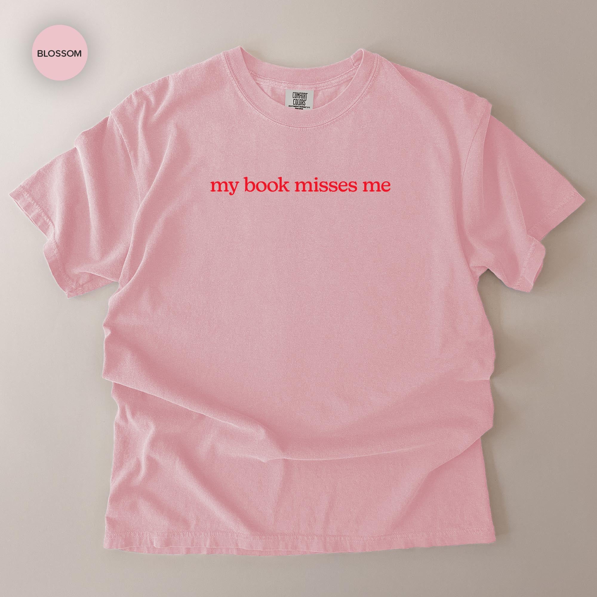 A pink t-shirt with the text "my book misses me" printed on it.