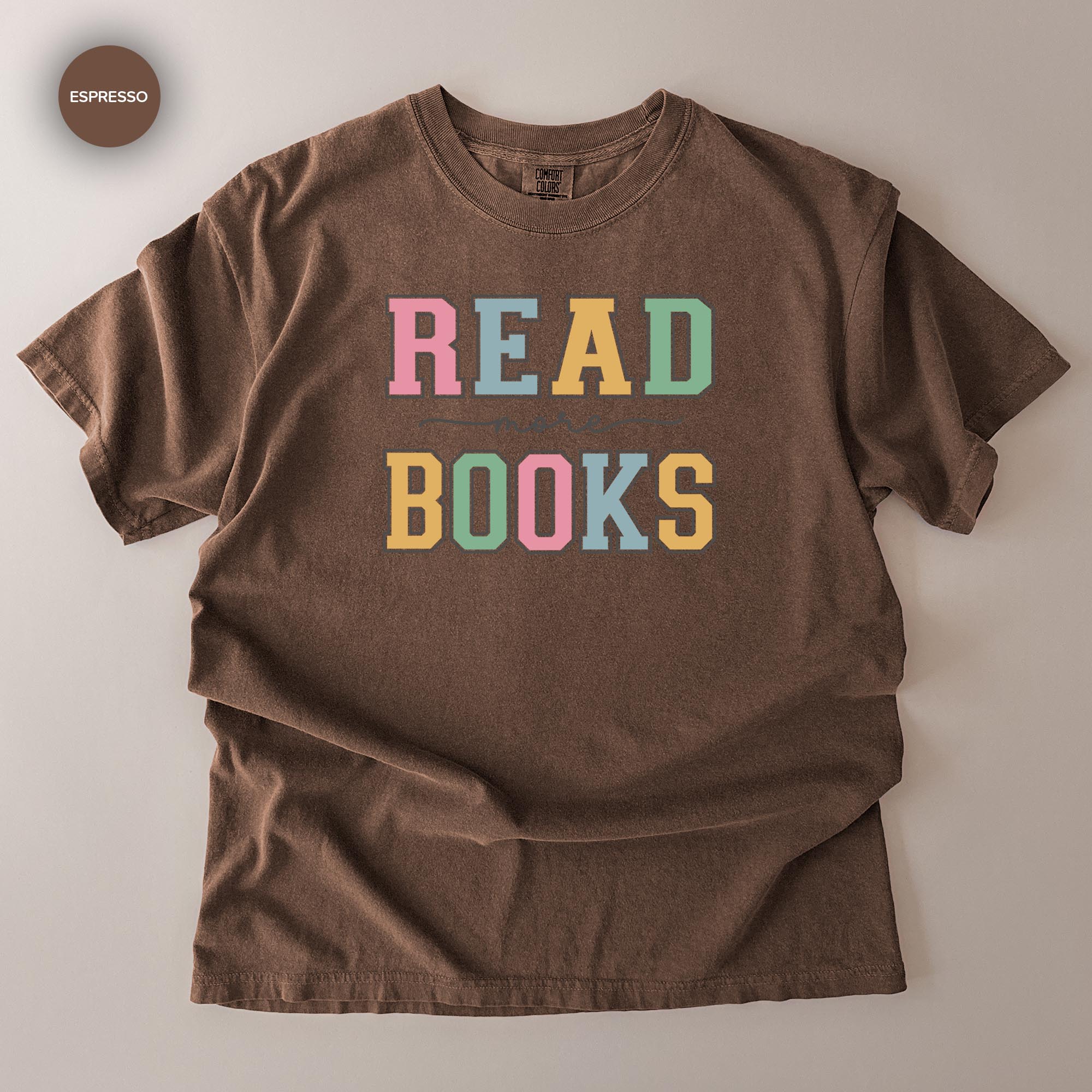 A brown t-shirt with the text "READ BOOKS" printed on it in a colorful, playful font.