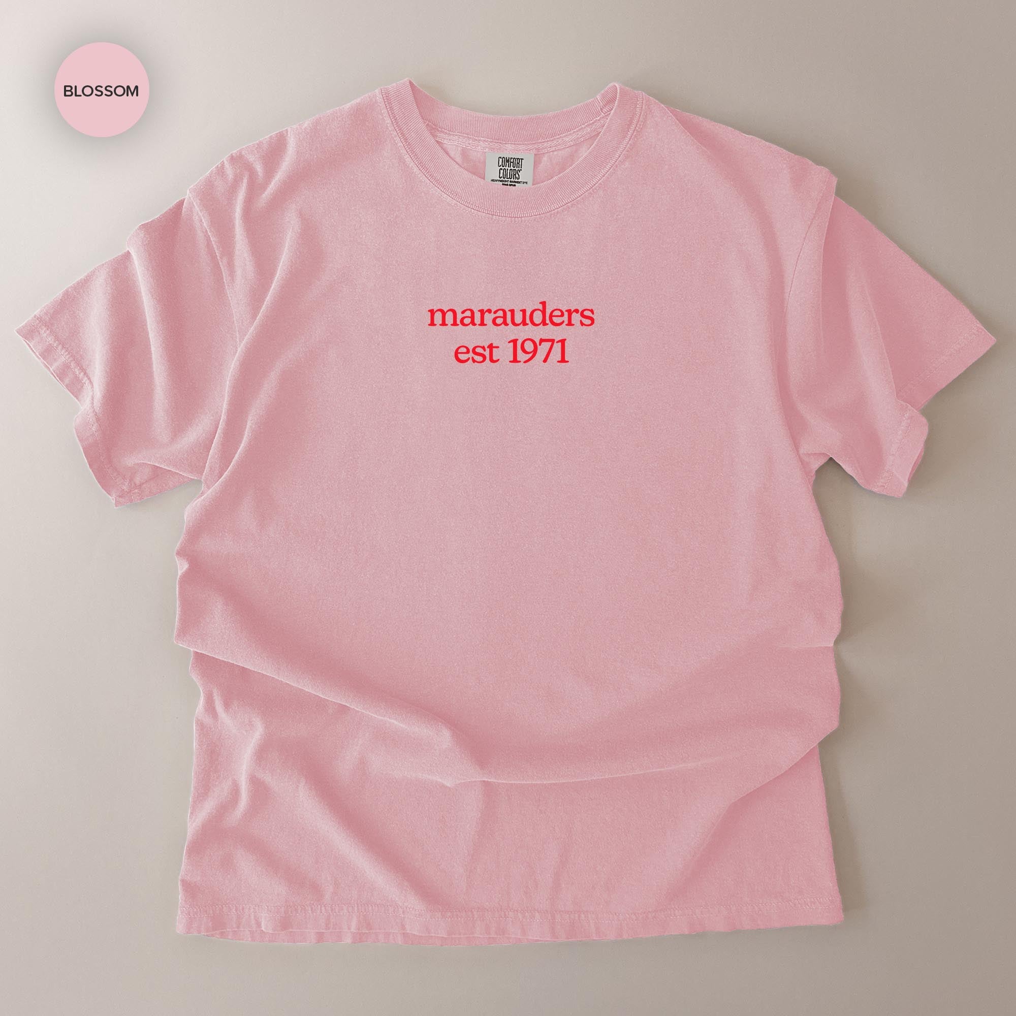 A pink t-shirt with the text "marauders est 1971" printed on it.