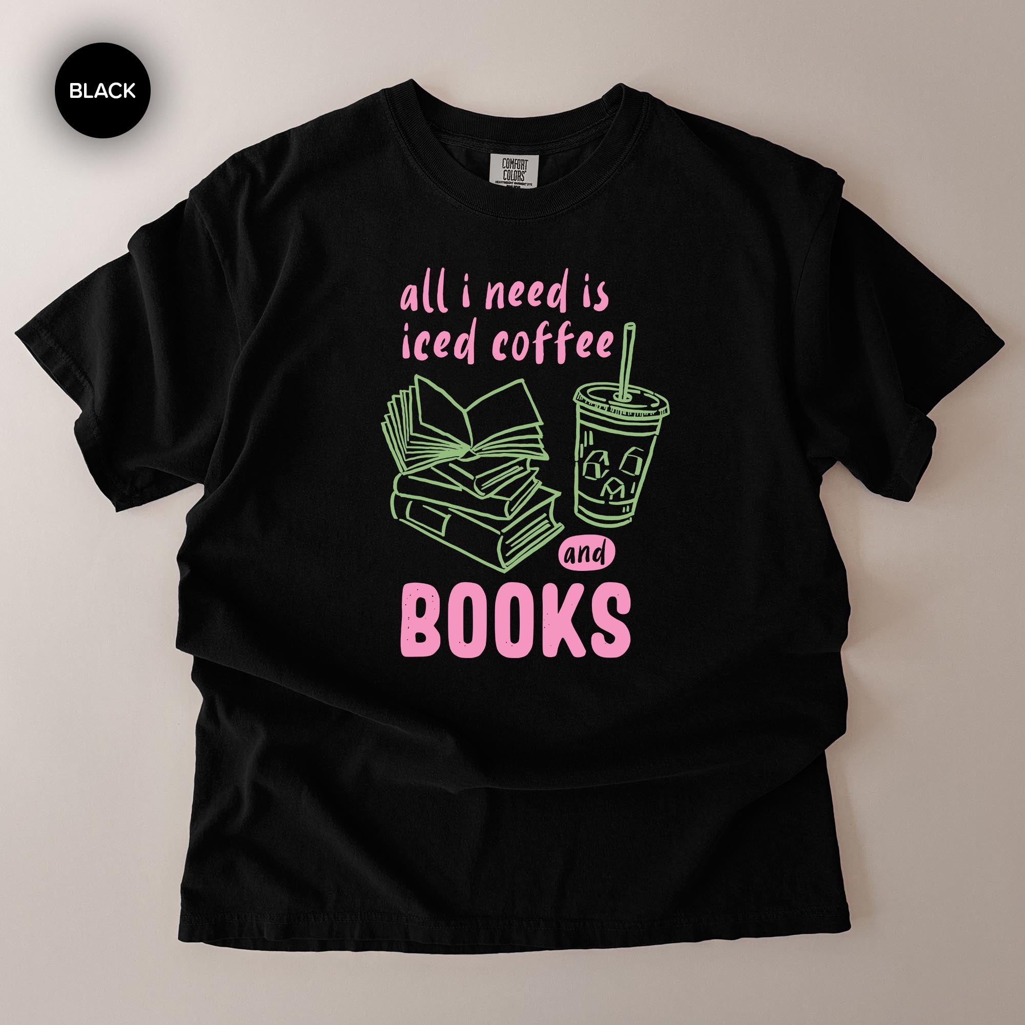 A black t-shirt with a graphic design that says "all I need is iced coffee and books" in pink and green text.