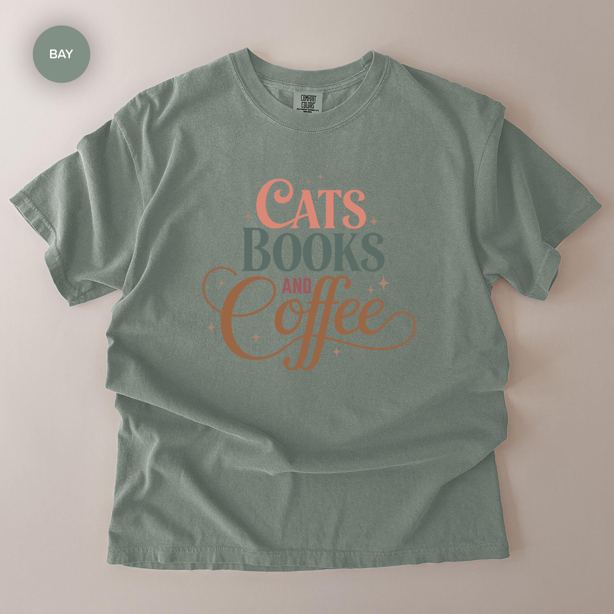A gray t-shirt with the text "CATS BOOKS AND COFFEE" printed on it.
