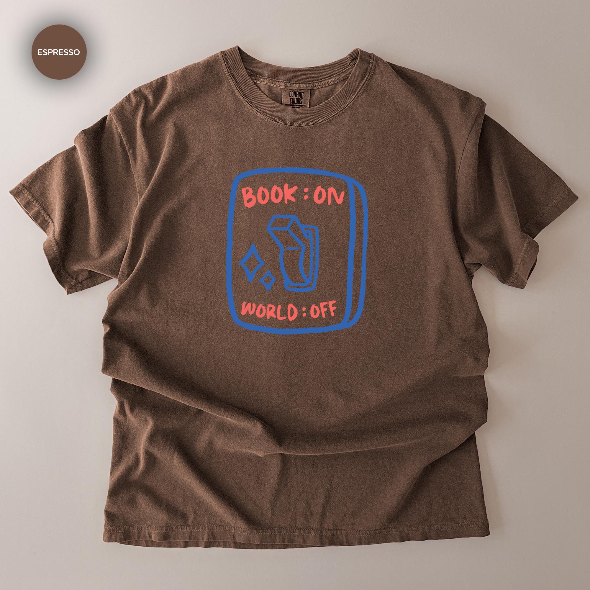 A brown t-shirt with a graphic design on it, featuring a book and the text "BOOK ON WORLD OFF" printed on it.