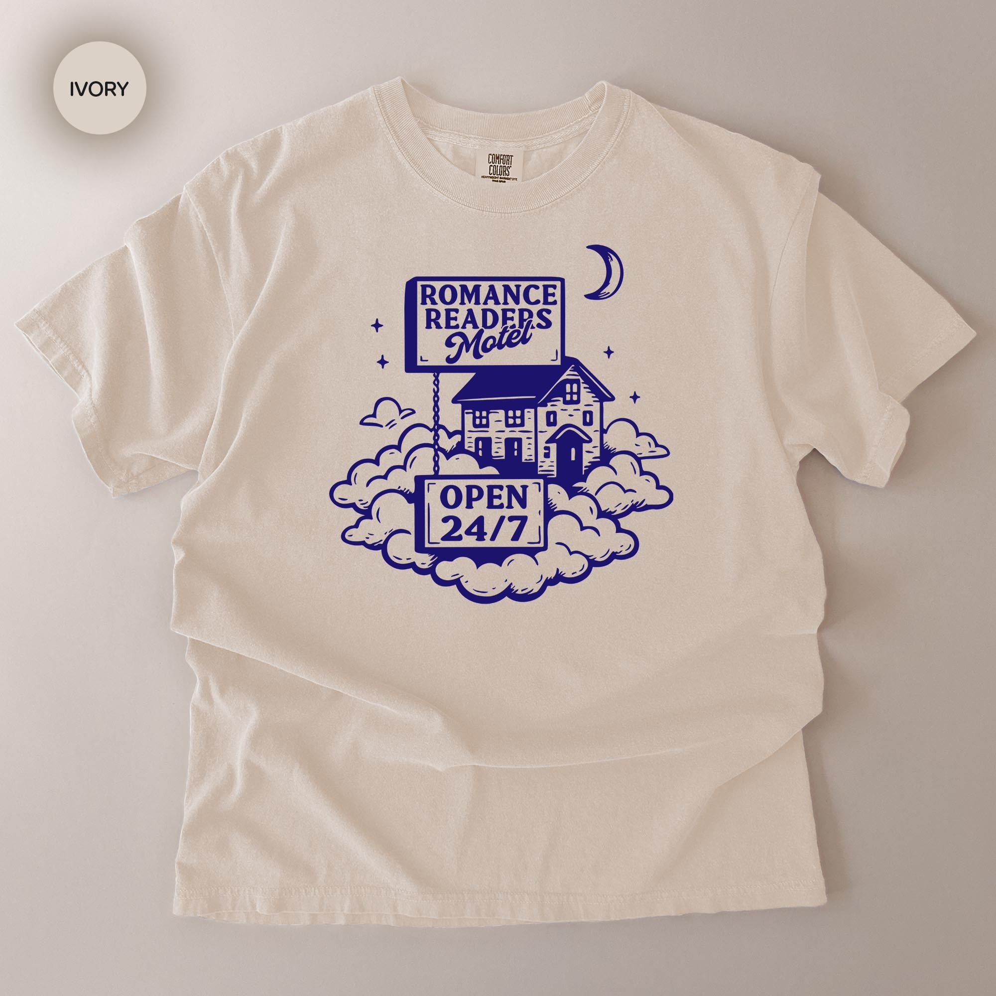 The image is a white t-shirt with a graphic design featuring a house, clouds, and a crescent moon, along with text that reads "ROMANCE READERS MOILET" and "OPEN 24/7".