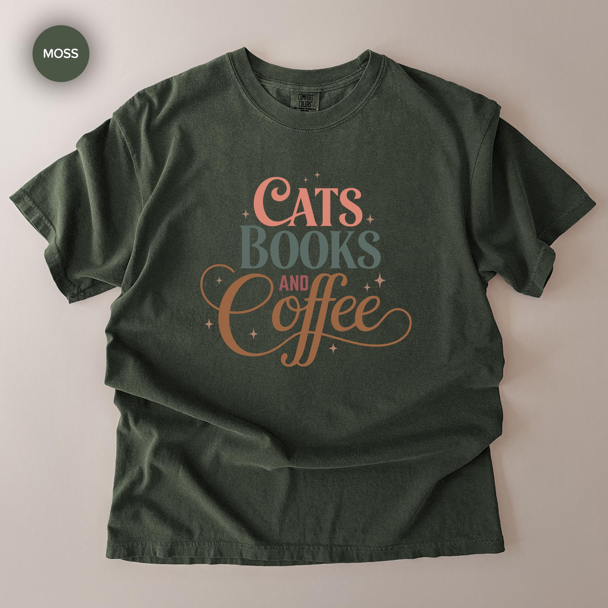 A green t-shirt with the text "CATS BOOKS AND COFFEE" printed on it.