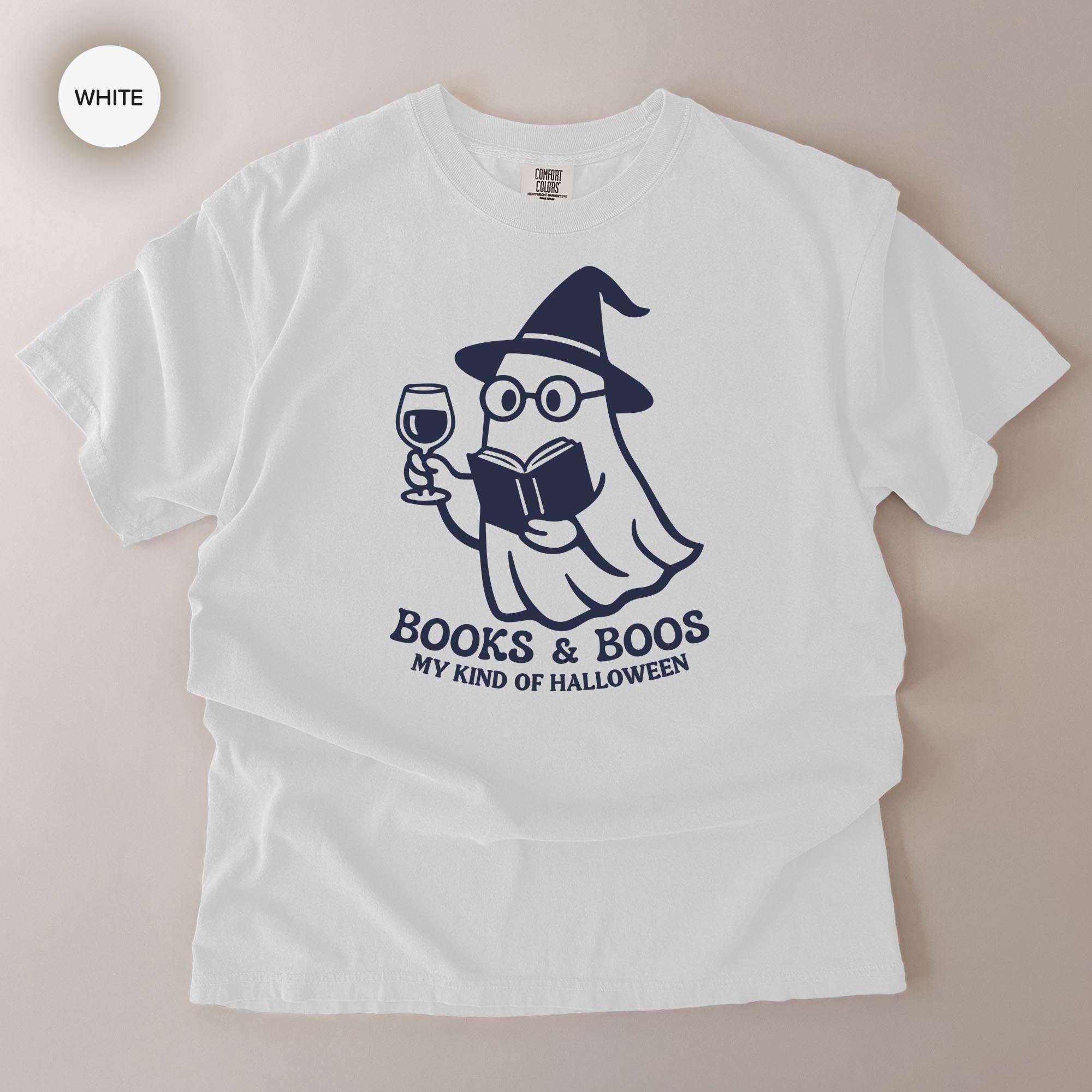 A white t-shirt with a graphic design depicting a ghost character holding a book and a wine glass, along with the text "Books & Boo's MY KIND OF HALLOWEEN".