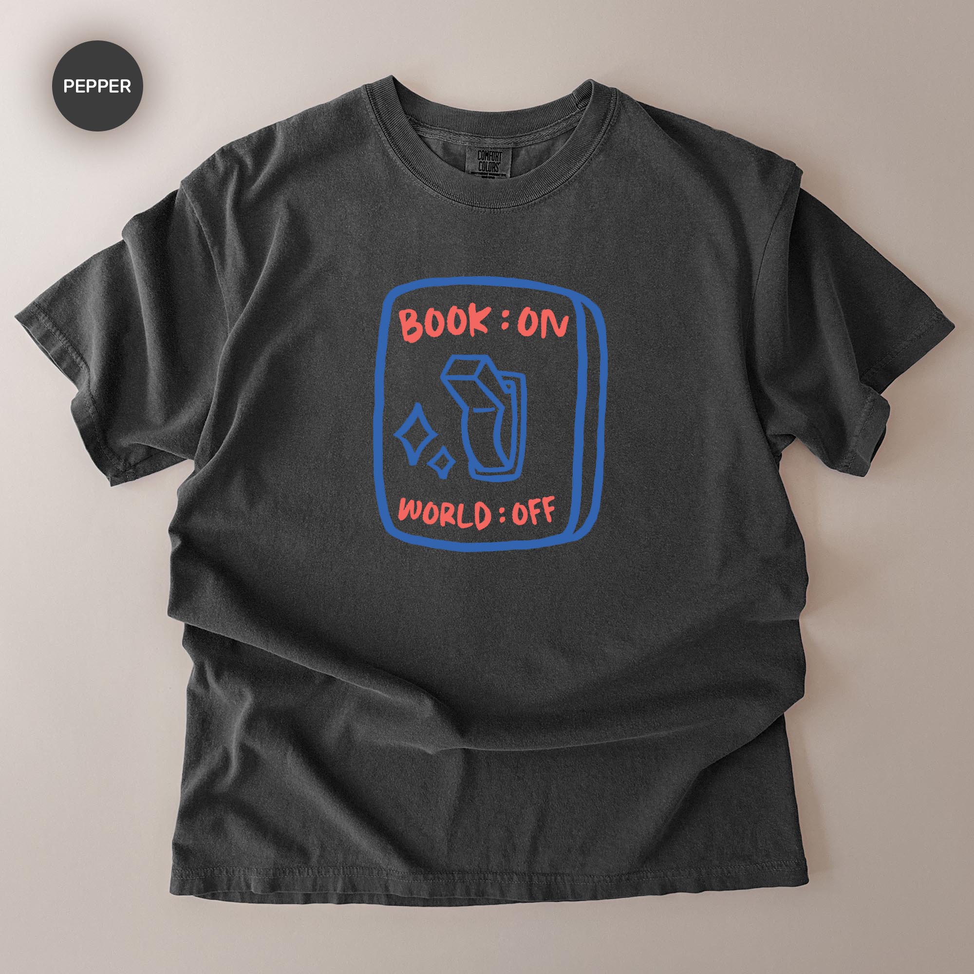A gray t-shirt with a graphic design on it, featuring a blue book icon and the text "BOOK ON WORLD OFF" printed on it.