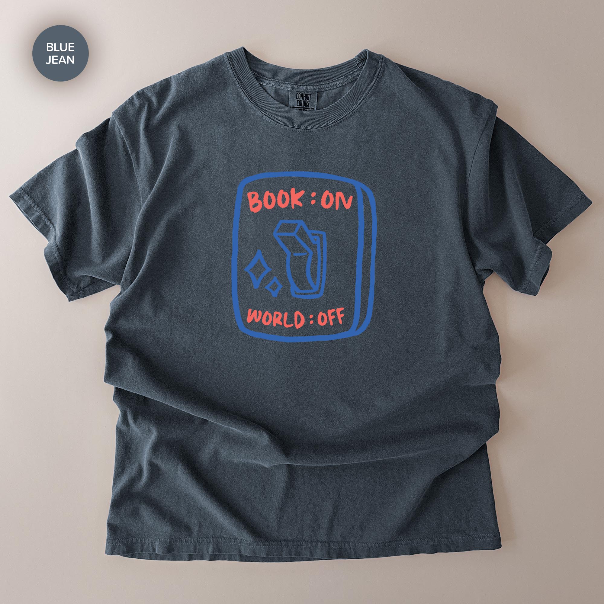 A gray t-shirt with a graphic design on it, featuring a blue book icon and the text "BOOK ON WORLD OFF" printed on it.