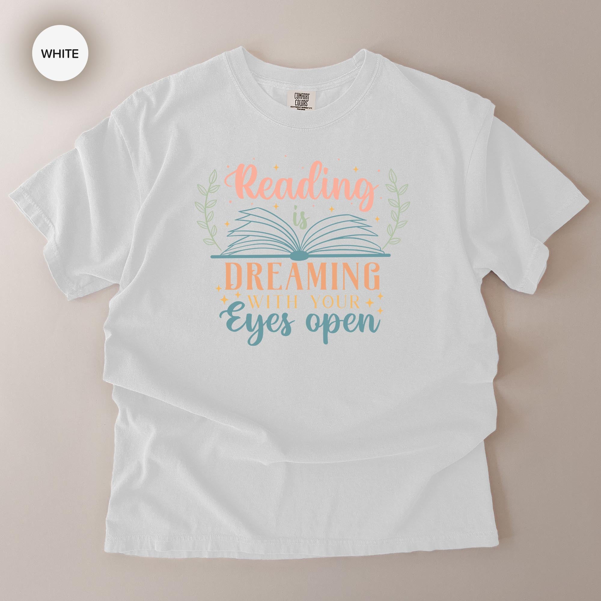 A white t-shirt with a printed design that says "Reading is Dreaming with your eyes open".