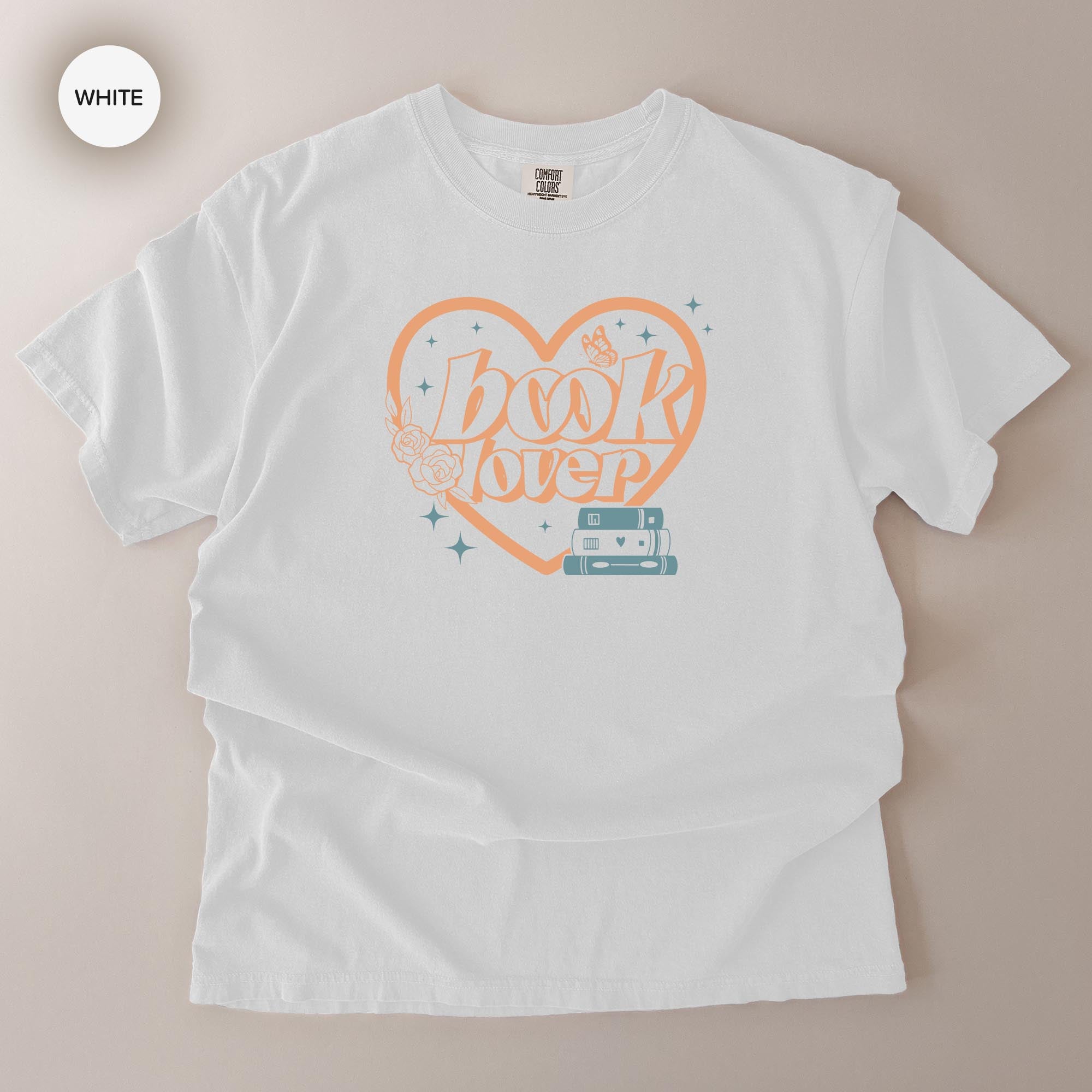 A white t-shirt with a graphic design featuring the text "BOOK LOVER" and a heart-shaped symbol with a book and a star.