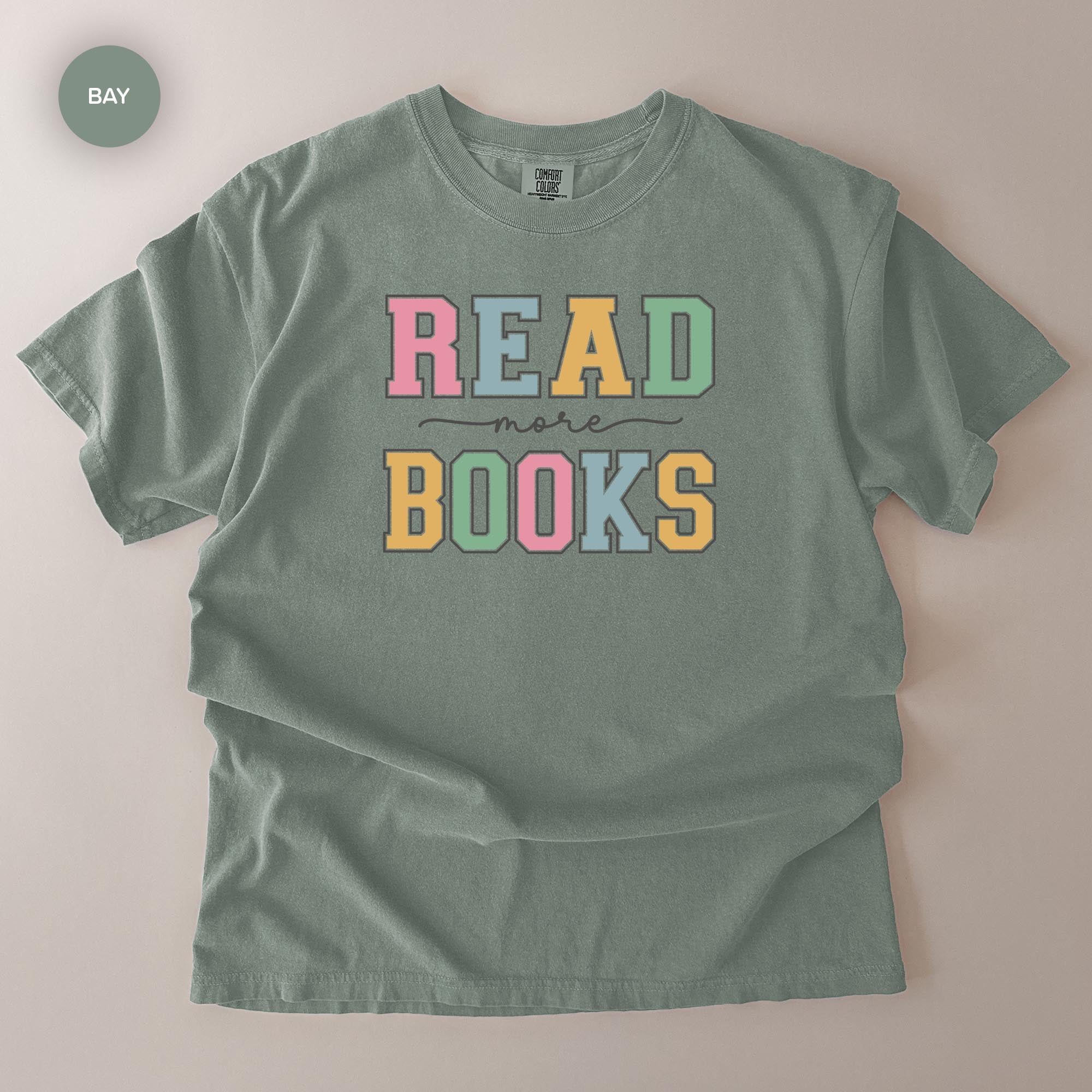 A gray t-shirt with the text "READ more BOOKS" printed on it in a colorful, playful font.