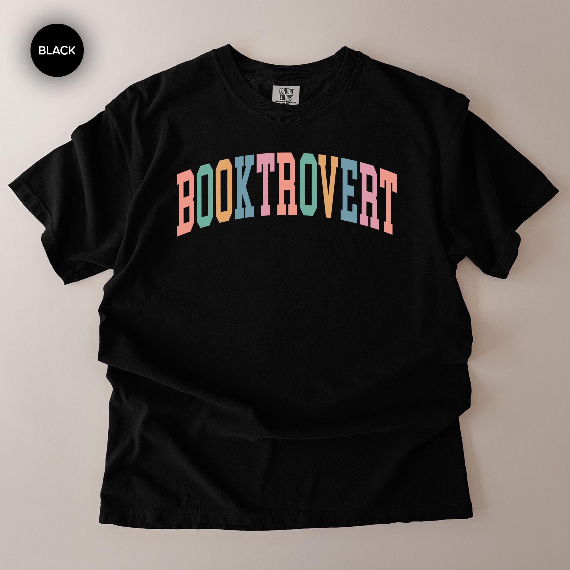 A black t-shirt with the text "BOOKTROVERT" printed in a colorful, multicolored font.