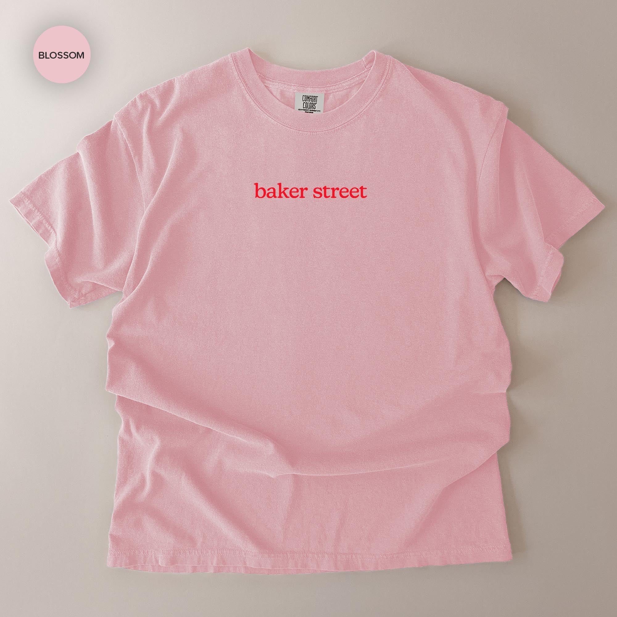 A pink t-shirt with the text "baker street" printed on it.