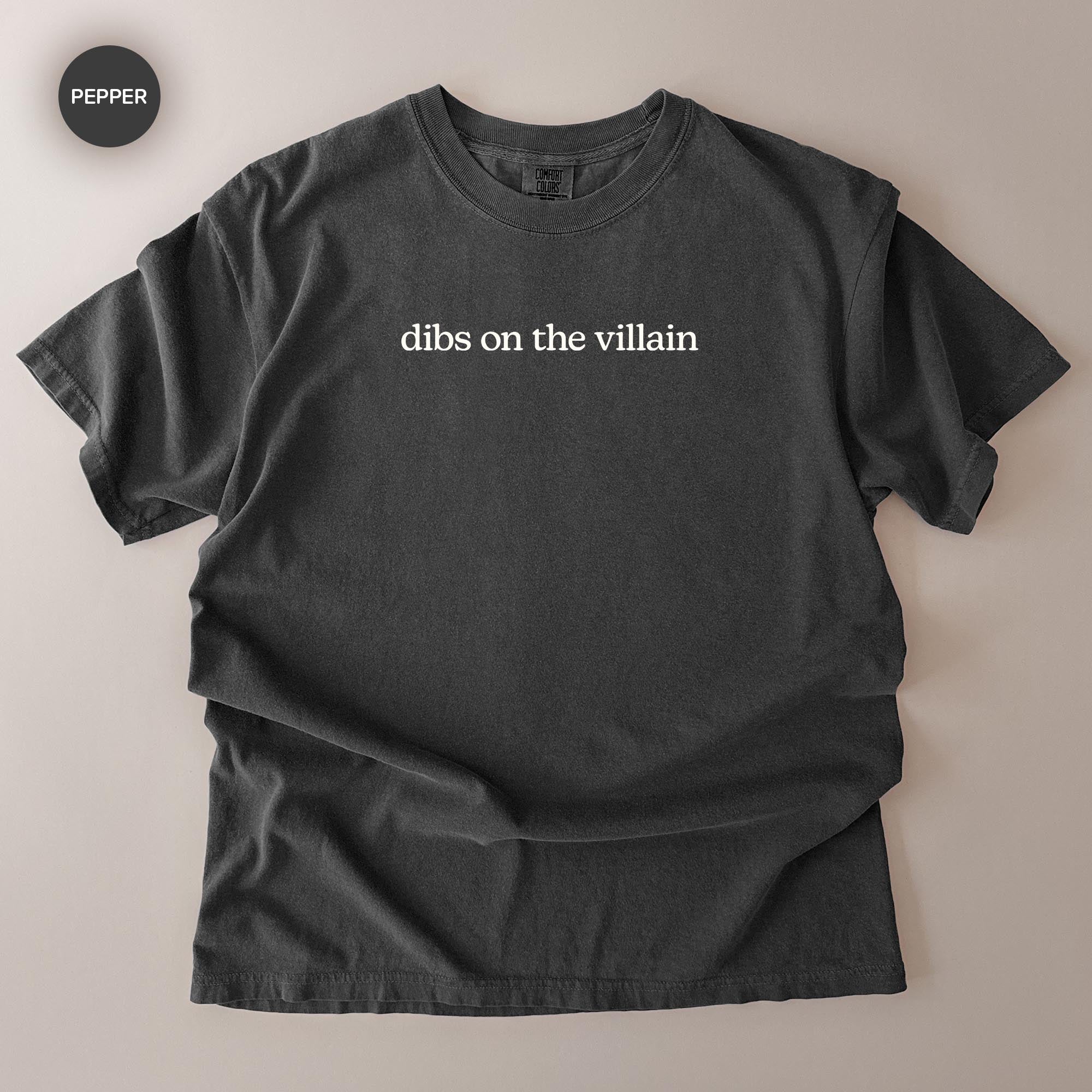 A black t-shirt with the text "dibs on the villain" printed on it.