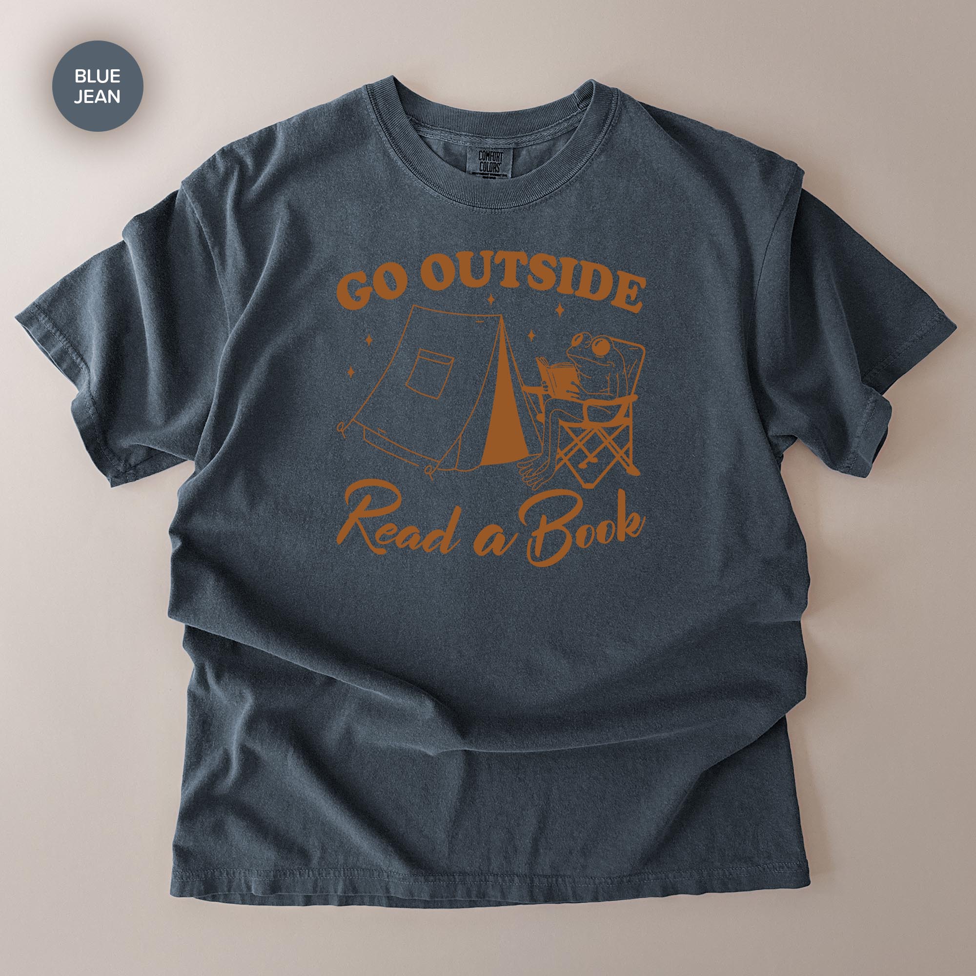 A gray t-shirt with a graphic design that says "Go Outside Read a Book" and includes a camping tent and a person sitting in a chair.