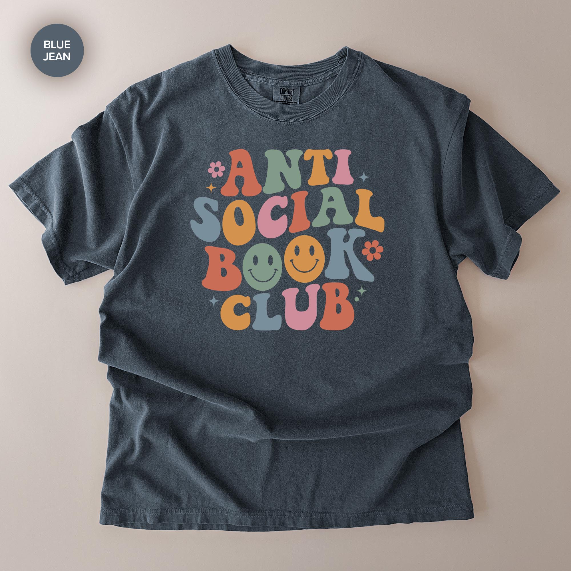 A gray t-shirt with a colorful graphic design that says "ANTI SOCIAL BOOK CLUB" in a playful, retro style.