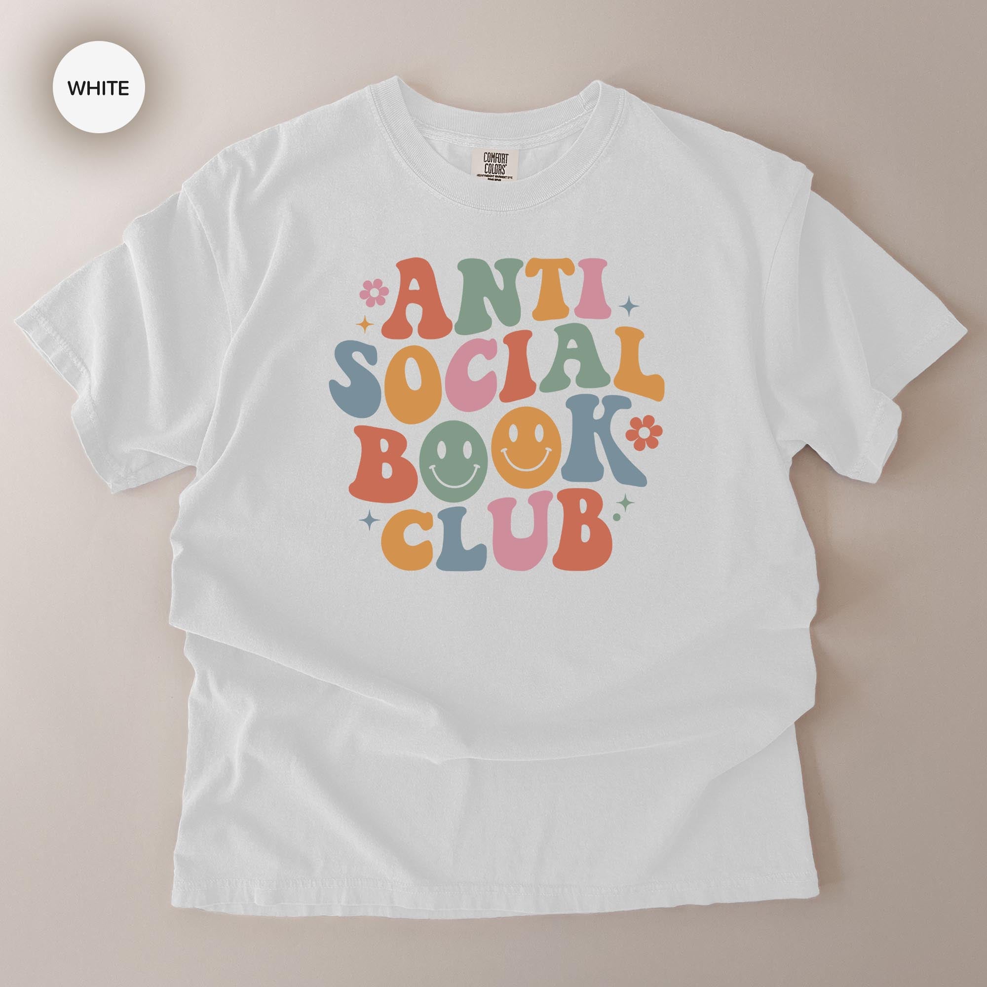 A white t-shirt with a colorful graphic design that says "ANTI SOCIAL BOOK CLUB" in a playful, retro style.