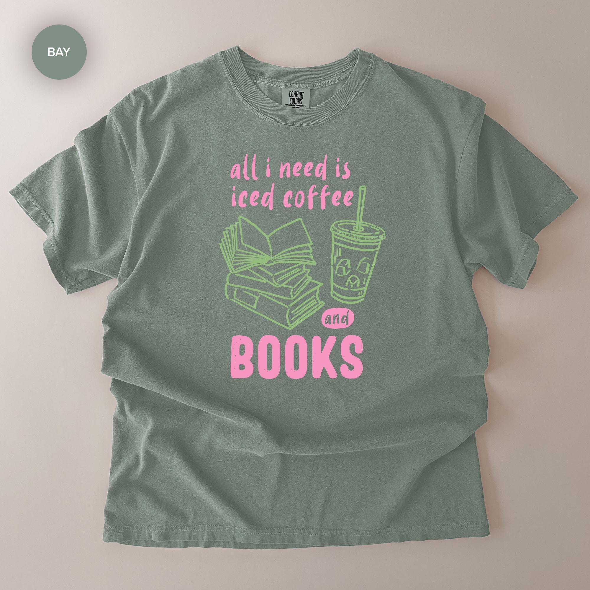 A gray t-shirt with a graphic design that says "all I need is iced coffee and books" in pink and green text.