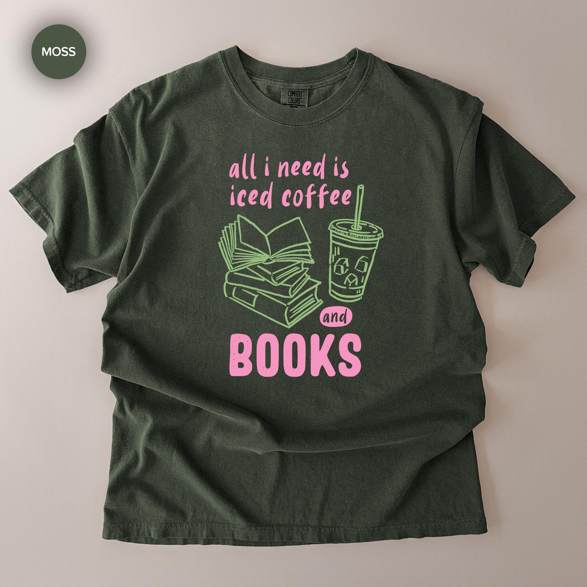 A green t-shirt with a graphic design that says "all I need is iced coffee and books" along with an illustration of a book and a cup of iced coffee.