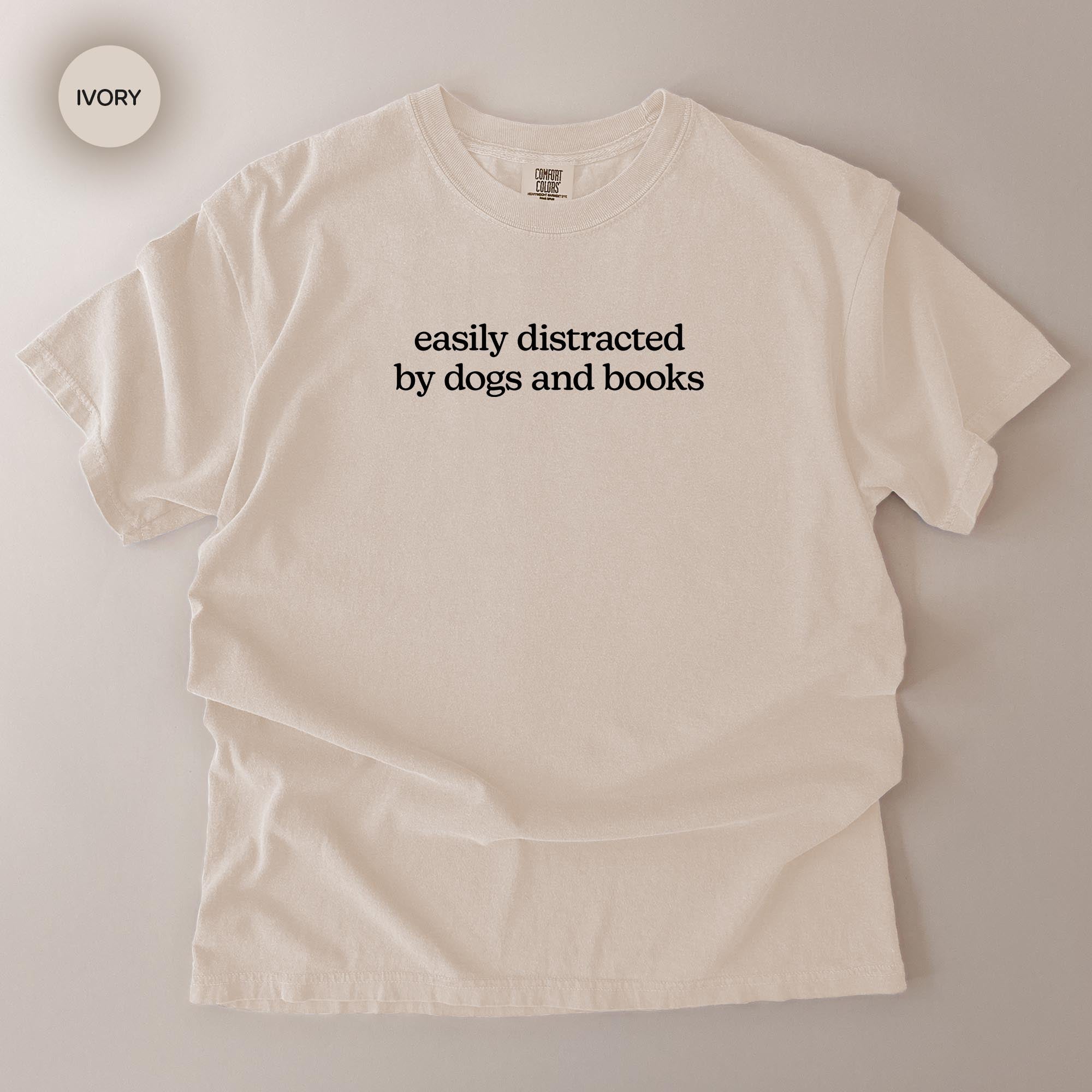 A white t-shirt with the text "easily distracted by dogs and books" printed on it.