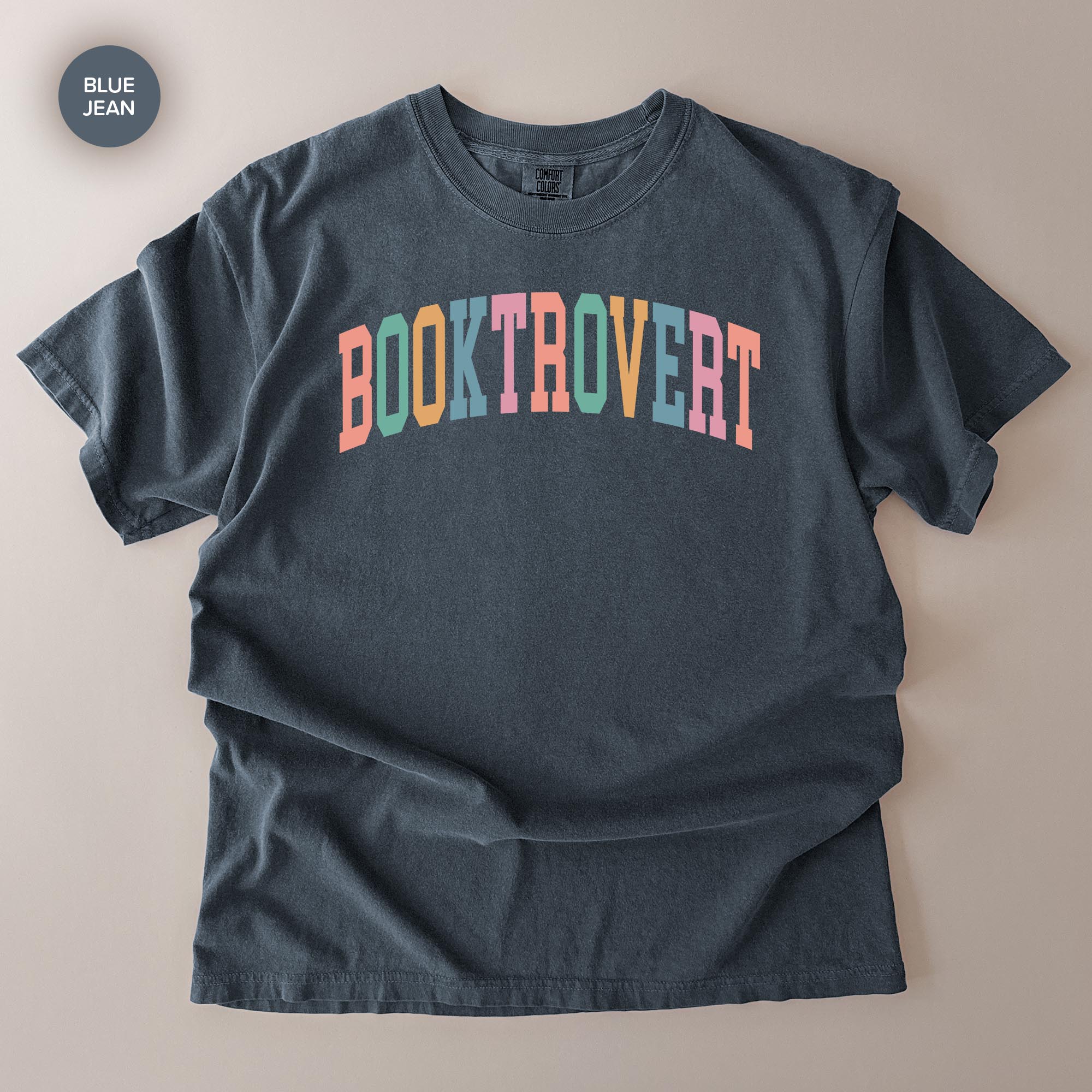 A dark gray t-shirt with the text "BOOKTROVERT" printed in a colorful, multicolored font.