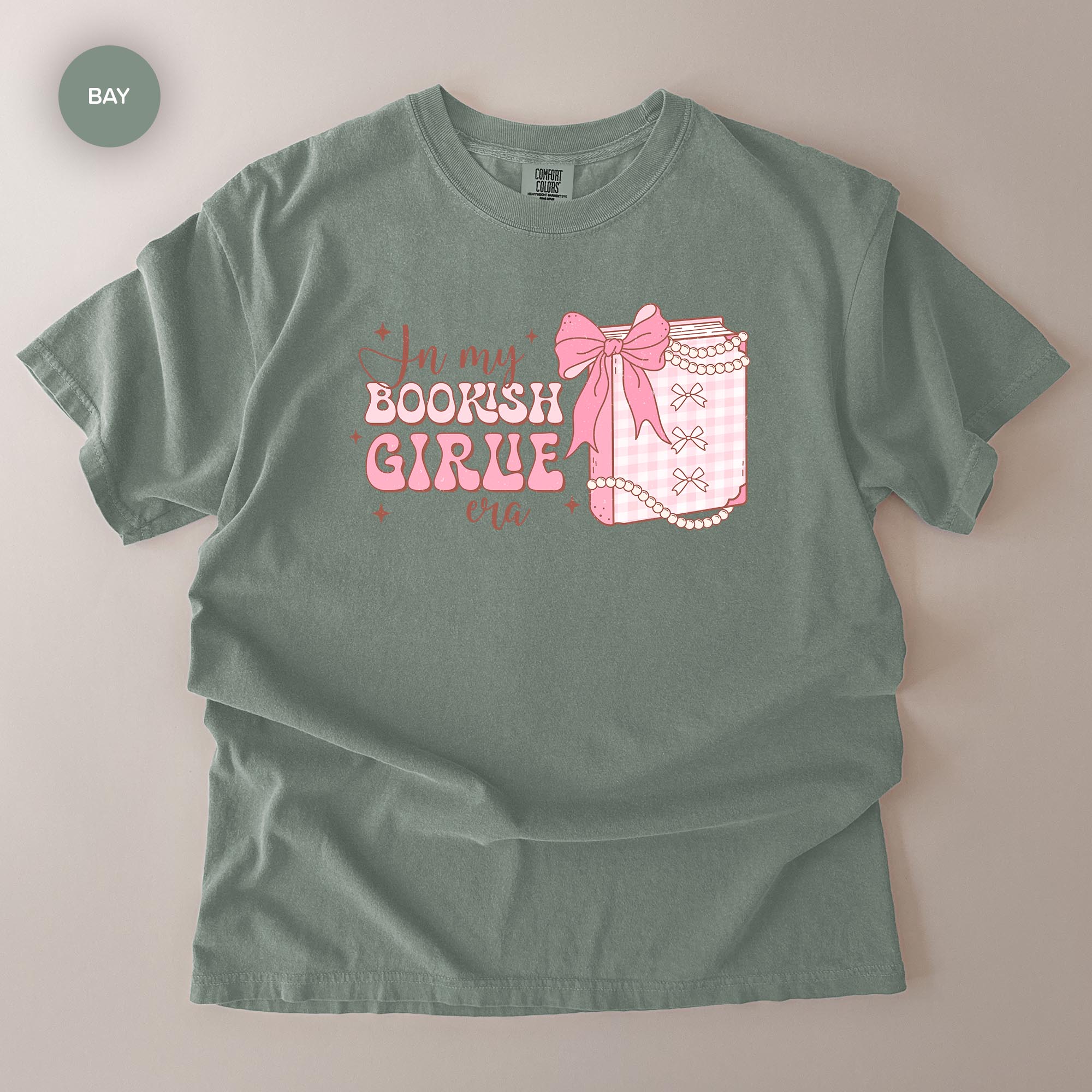 A gray t-shirt with a graphic design featuring a bow and the text "In my BOOKISH GIRLE era" printed on it.