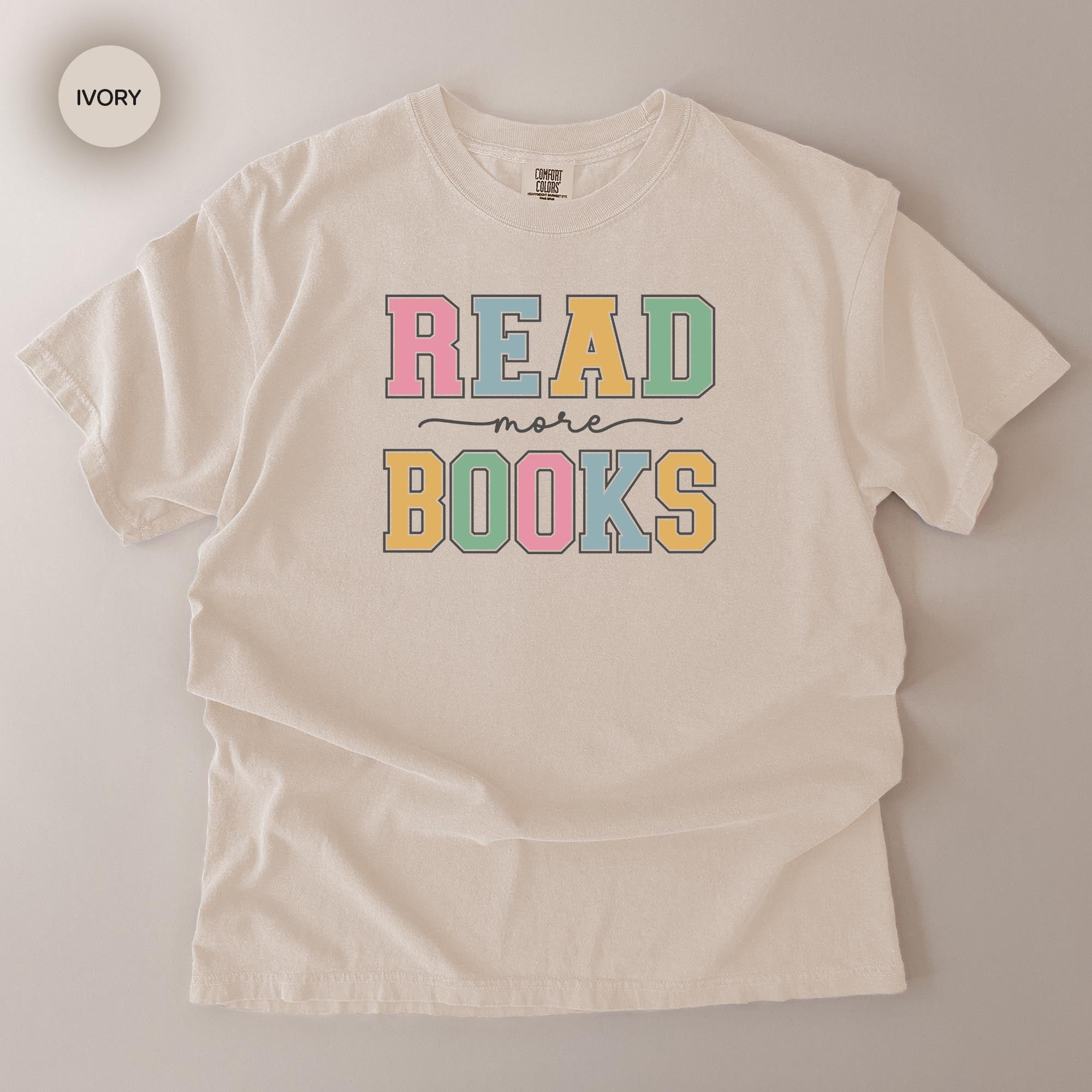 A white t-shirt with the text "READ more BOOKS" printed on it in a colorful, playful font.