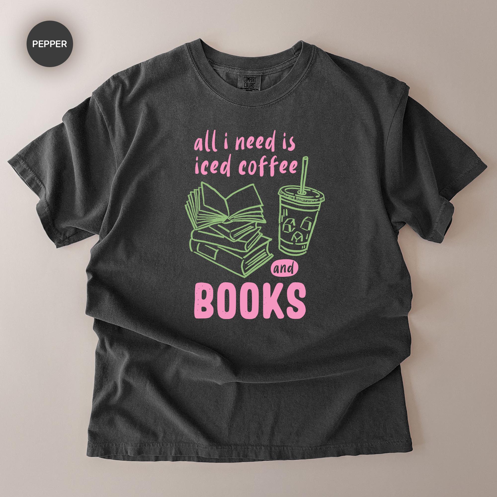 A black t-shirt with a graphic design that says "all I need is iced coffee and books" in pink and green text.