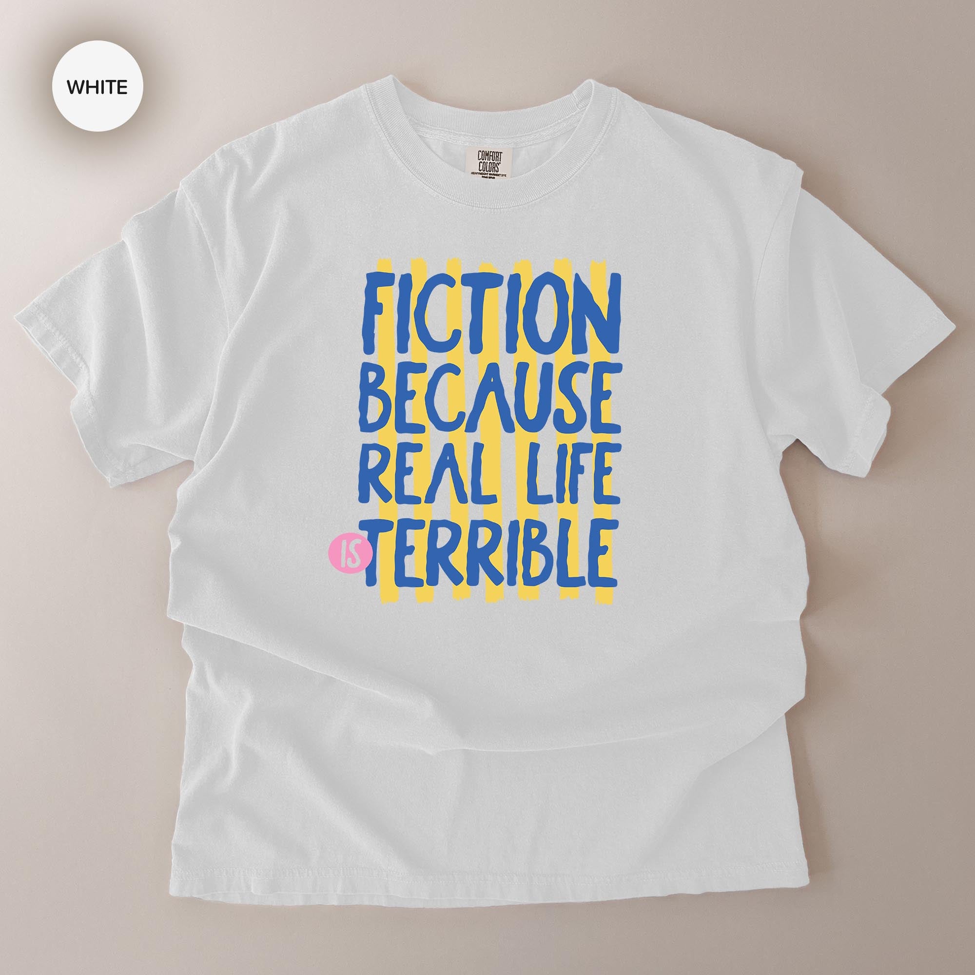 A white t-shirt with a printed message that reads "FICTION BECAUSE REAL LIFE IS TERRIBLE" in blue and yellow text.