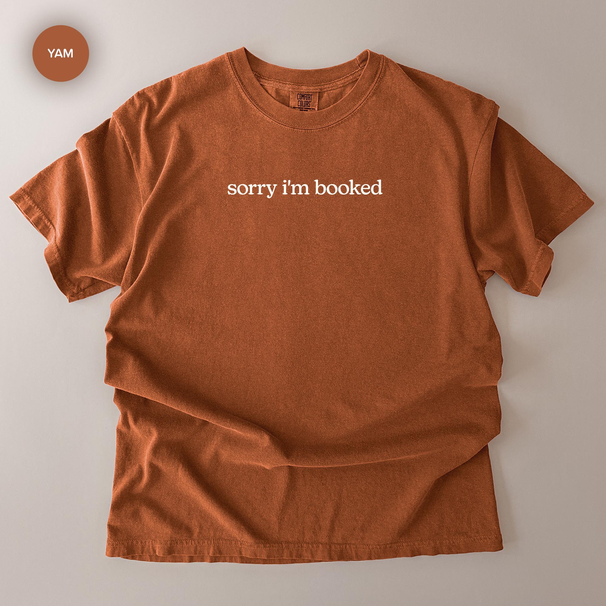 a brown t-shirt with the text "Sorry I'm booked" printed on it.