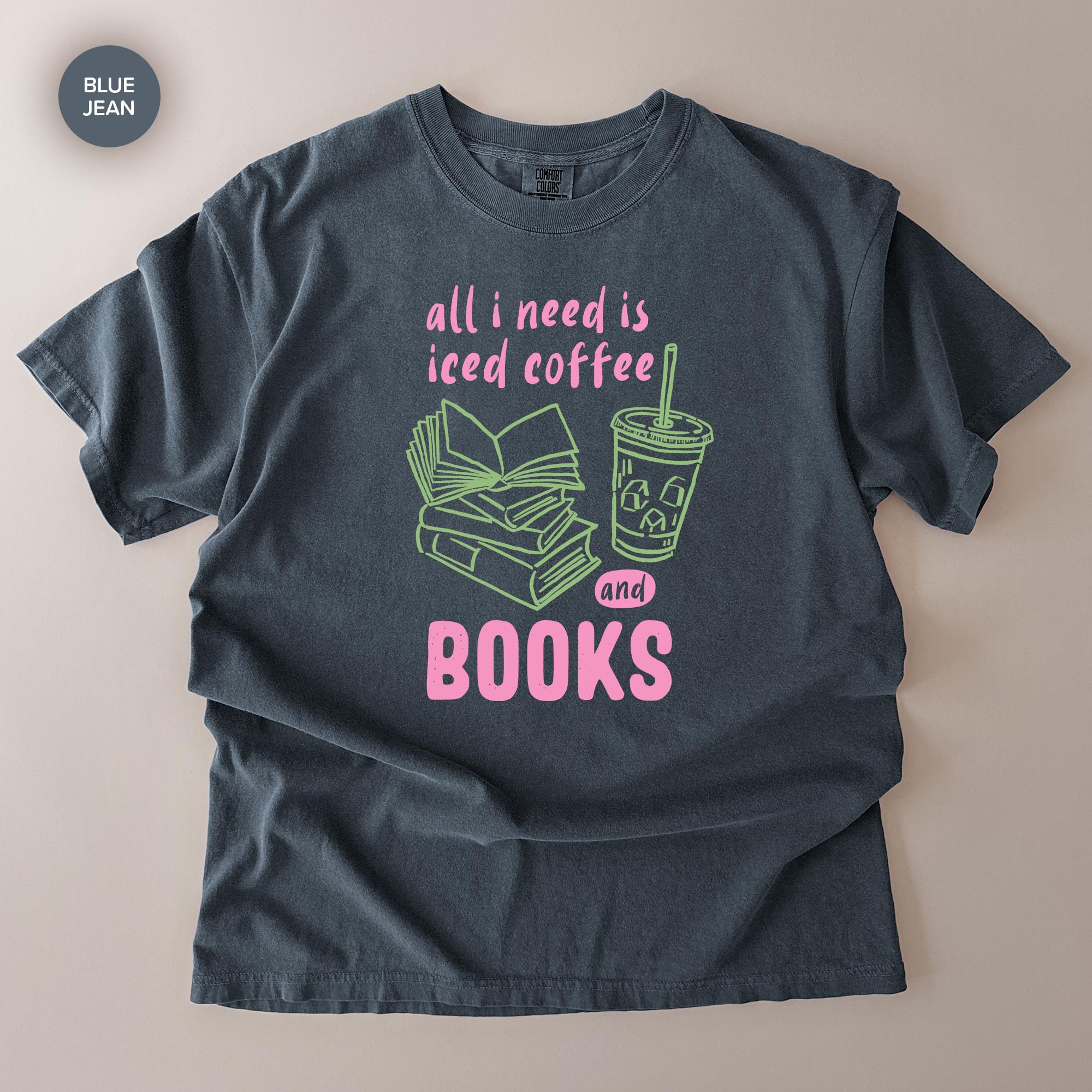 A gray t-shirt with a graphic design that says "all I need is iced coffee and books" in pink and green text.
